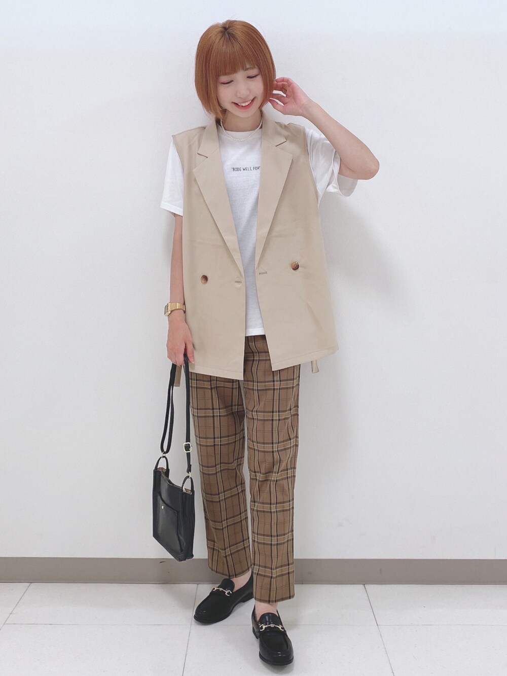 ホワイト系のTシャツ/カットソー、ベージュ系のベスト、ブラウン系のパンツを着用したレディースの秋コーディネートの4枚目の写真