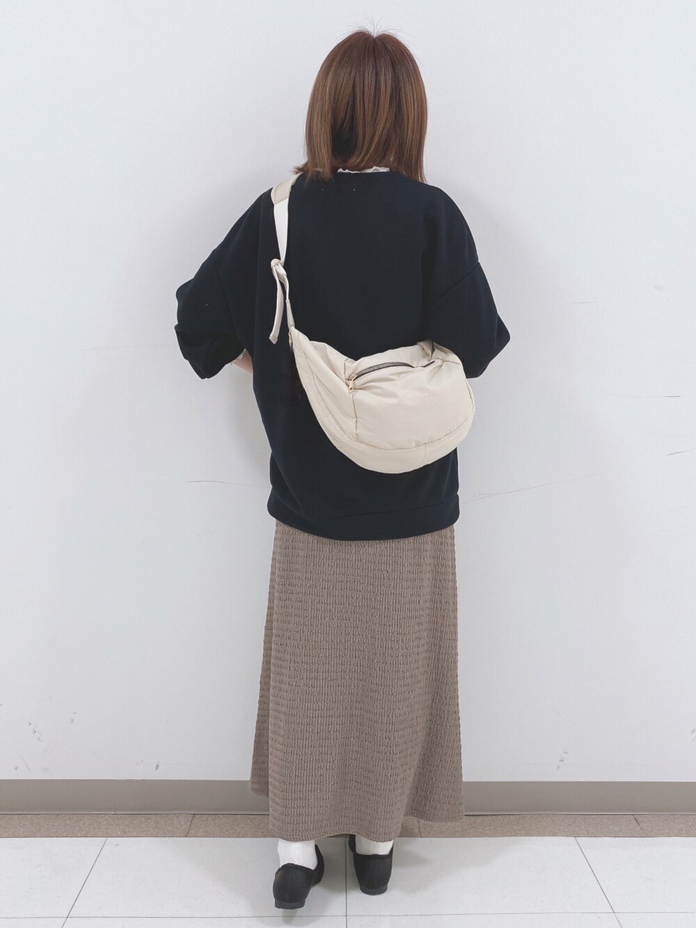 ブラック系のスウェット、ベージュ系のスカート、ブラック系のパンプスを着用したレディースの春コーディネートの3枚目の写真