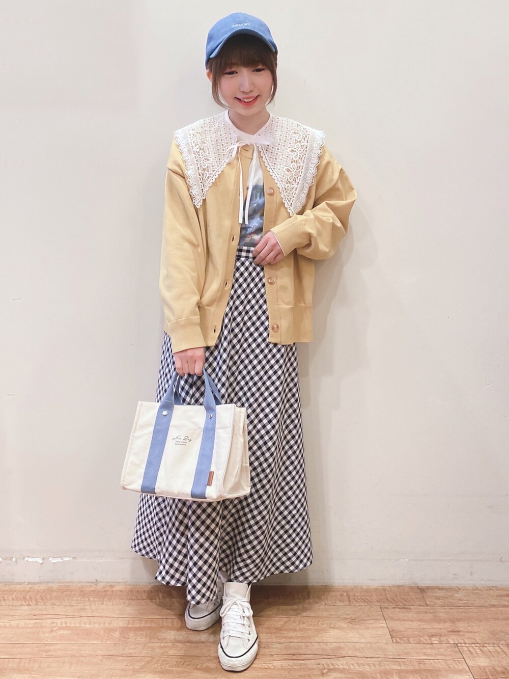 ホワイト系のTシャツ/カットソー、イエロー系のニット/セーター、ブラック系のスカートを着用したレディースの春コーディネートの4枚目の写真