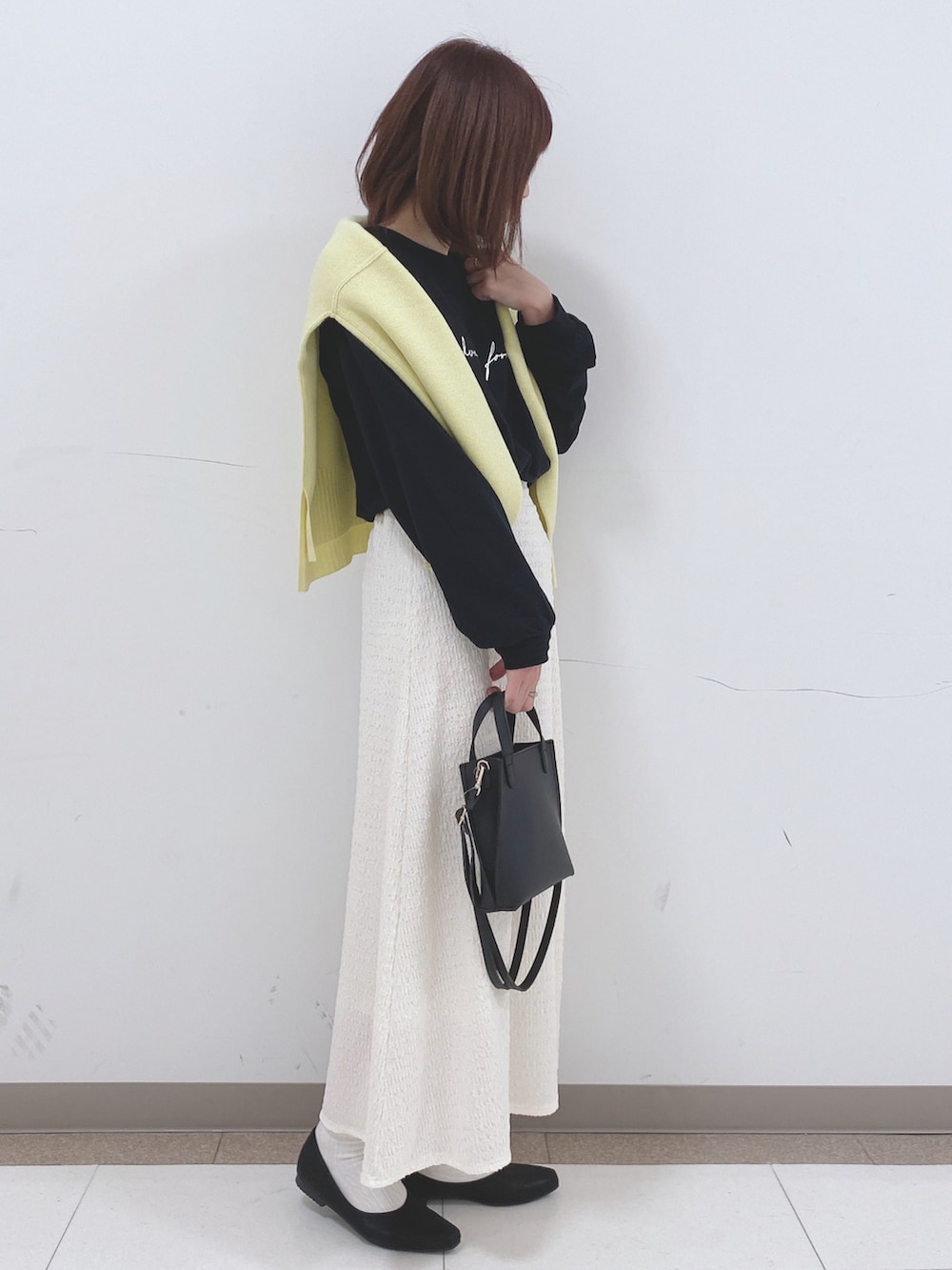 ブラック系のTシャツ/カットソー、イエロー系のニット/セーター、ブラック系のパンプスを着用したレディースの冬コーディネートの2枚目の写真