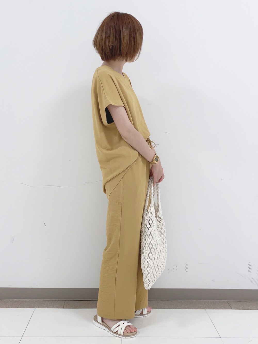 ホワイト系のトートバッグ、ホワイト系のサンダル、イエロー系のチュニックを着用したレディースの夏コーディネートの2枚目の写真