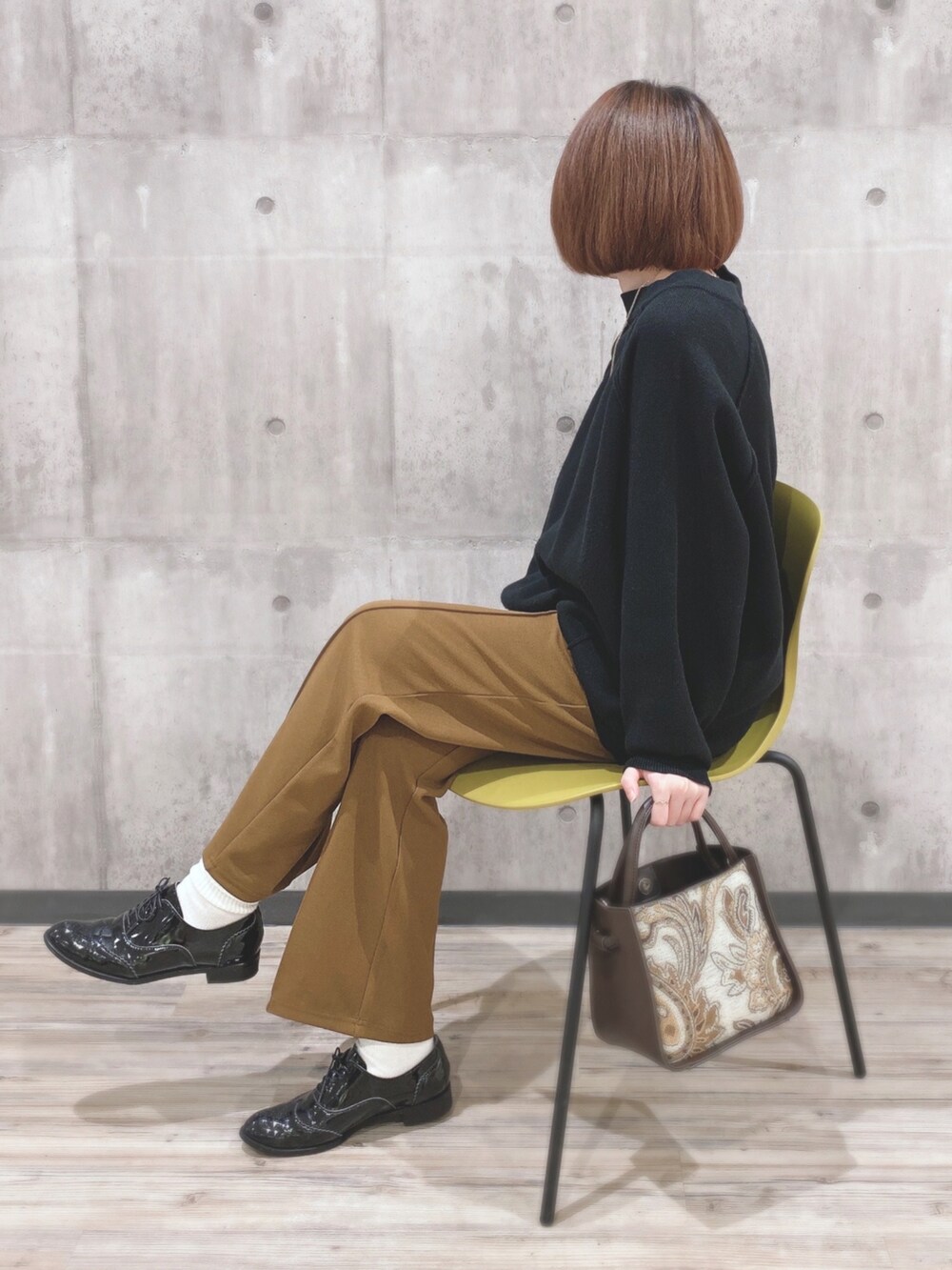 ブラック系のニット/セーター、イエロー系のその他パンツ、ブラウン系のトートバッグを着用したレディースの秋コーディネートの2枚目の写真