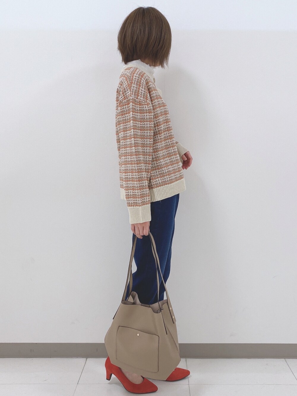 オレンジ系のカーディガン/ボレロ、ホワイト系のTシャツ/カットソー、ブルー系のデニムパンツを着用したレディースの秋コーディネートの2枚目の写真