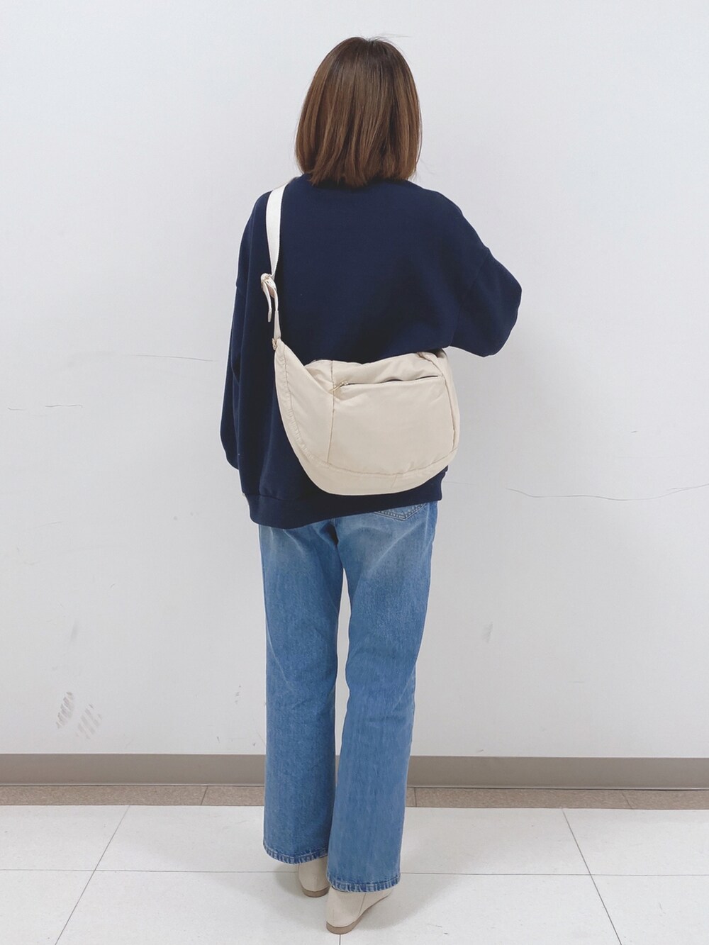 ブルー系のスウェット、ホワイト系のパンプス、ベージュ系のショルダーバッグを着用したレディースの冬コーディネートの3枚目の写真