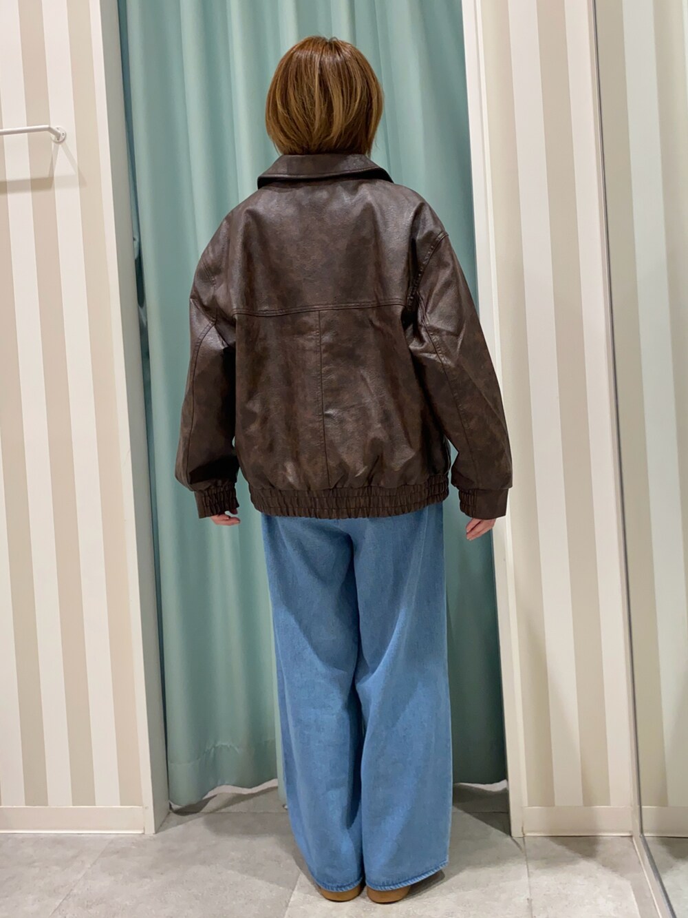 ブラウン系のブルゾン、ベージュ系のニット/セーター、ブルー系のその他パンツを着用したレディースの秋コーディネートの3枚目の写真