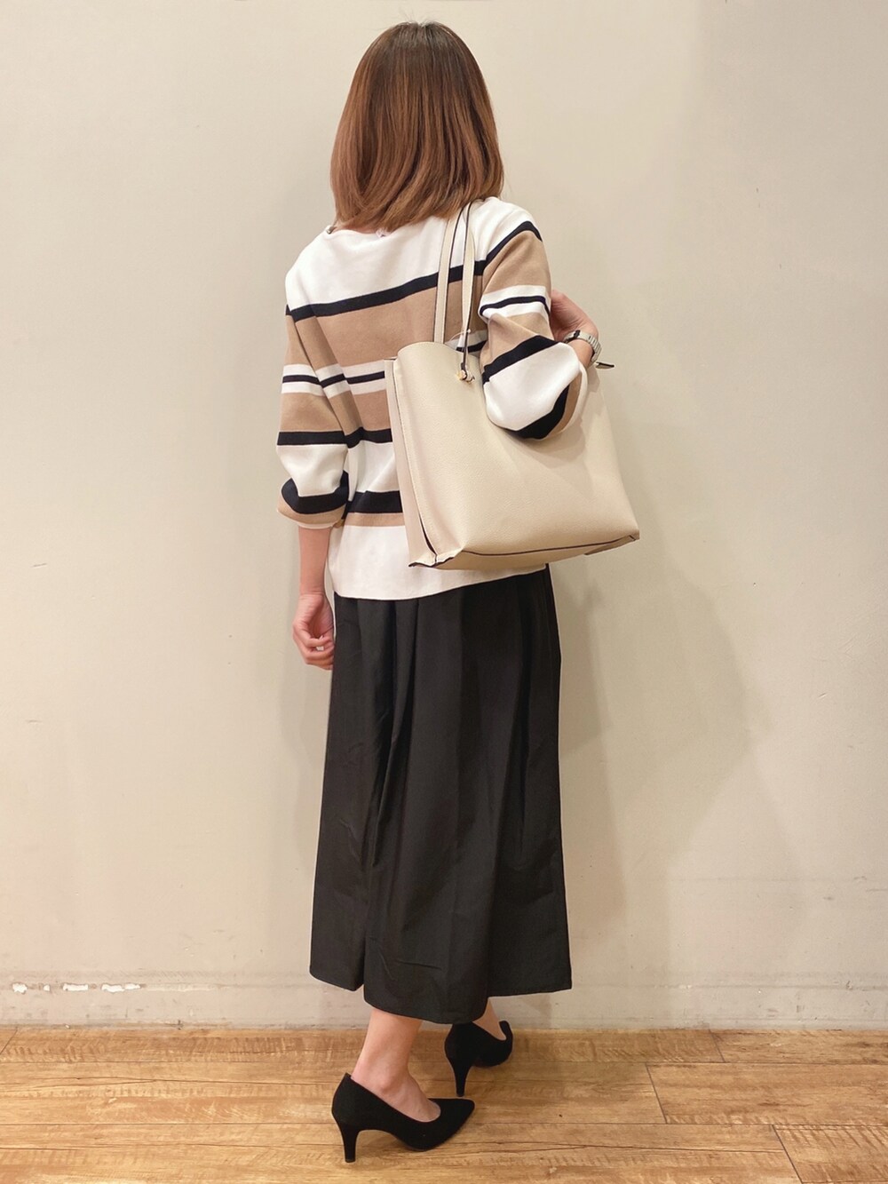 ベージュ系のニット/セーター、ブラック系のスカート、ホワイト系のトートバッグを着用したレディースの冬コーディネートの3枚目の写真