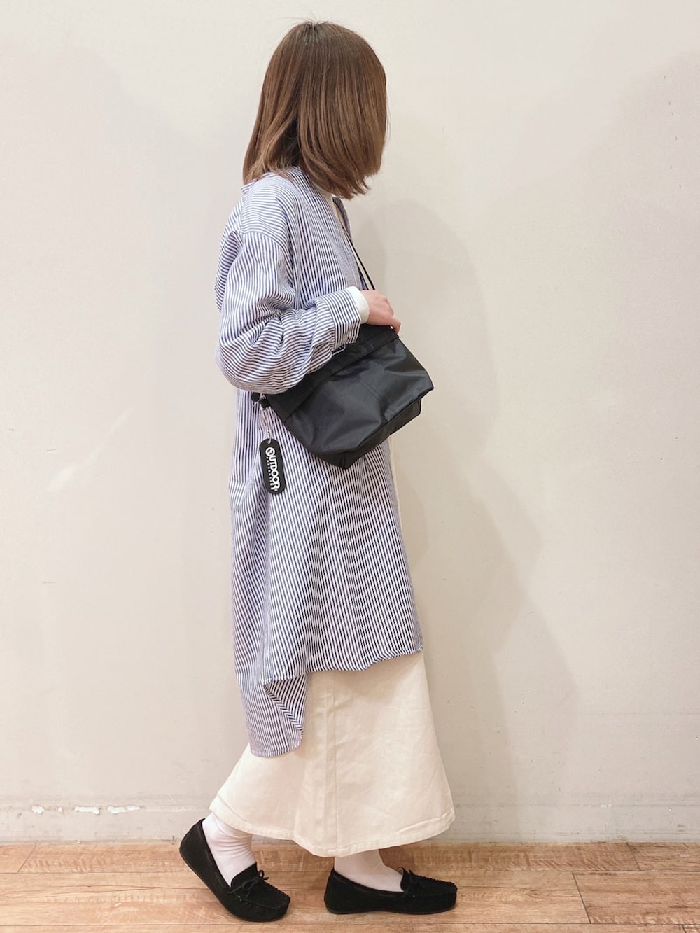 ホワイト系のスカート、ブラック系のショルダーバッグ、ブラック系のその他シューズを着用したレディースの春コーディネートの2枚目の写真