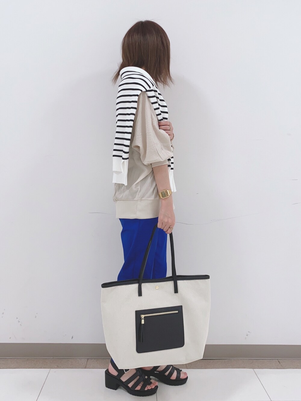 ベージュ系のシャツ/ブラウス、ブラック系のニット/セーター、ブルー系のその他パンツを着用したレディースの春コーディネートの2枚目の写真