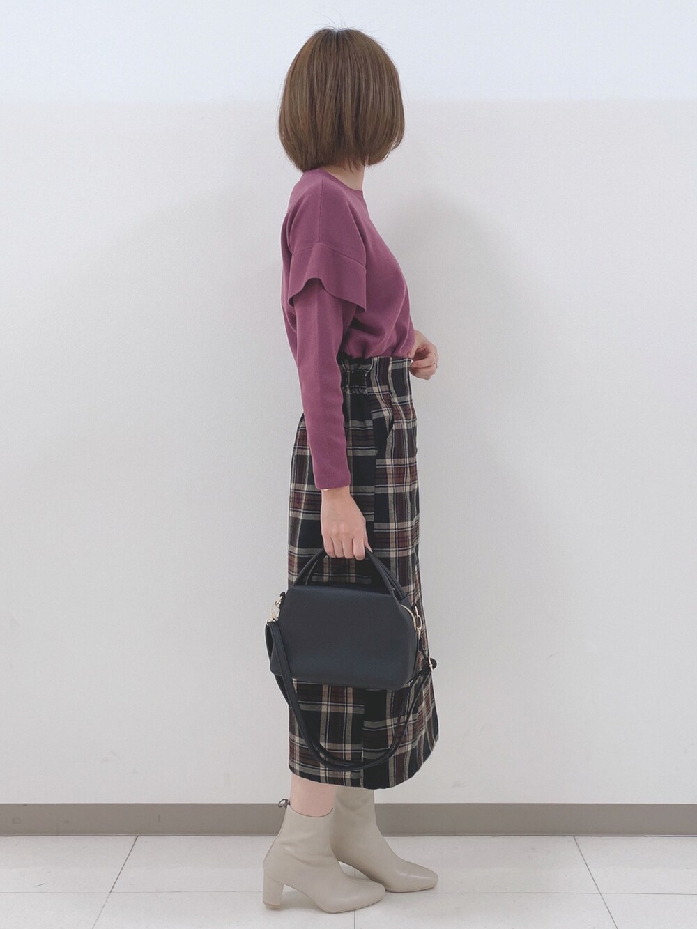 ピンク系のニット/セーター、ブラック系のスカート、ホワイト系のブーツを着用したレディースの秋コーディネートの2枚目の写真