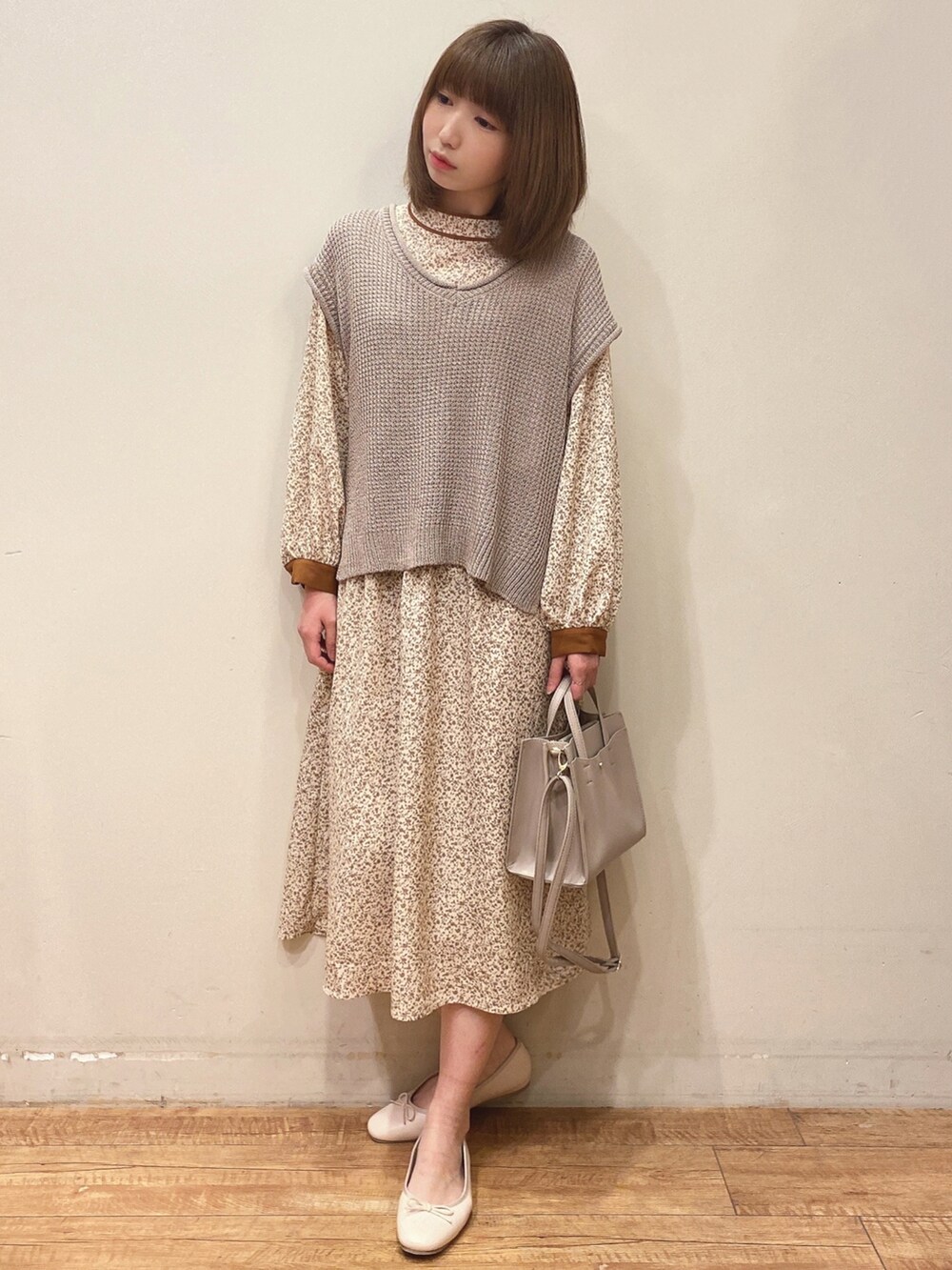 ベージュ系のベスト、ベージュ系のワンピース、グレー系のショルダーバッグを着用したレディースの春コーディネートの2枚目の写真