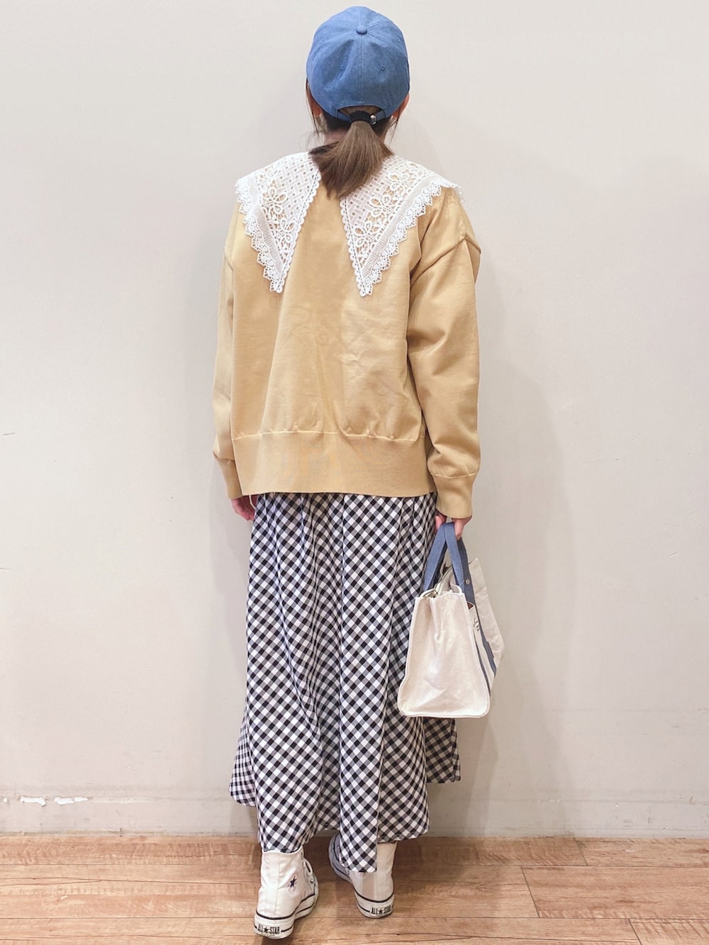 ホワイト系のTシャツ/カットソー、イエロー系のニット/セーター、ブラック系のスカートを着用したレディースの春コーディネートの3枚目の写真