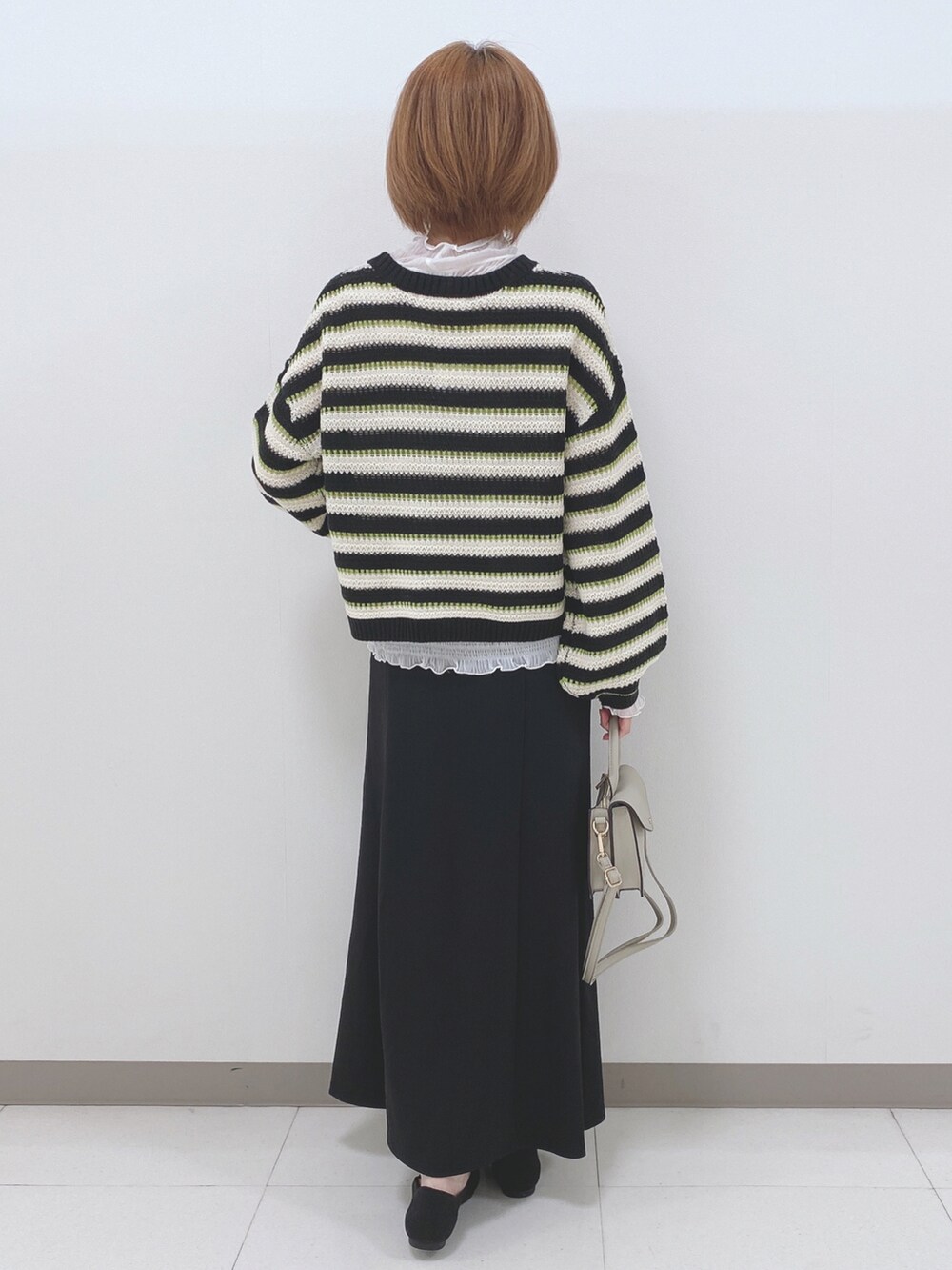 ブラック系のニット/セーター、ホワイト系のTシャツ/カットソー、ブラック系のスカートを着用したレディースの秋コーディネートの3枚目の写真