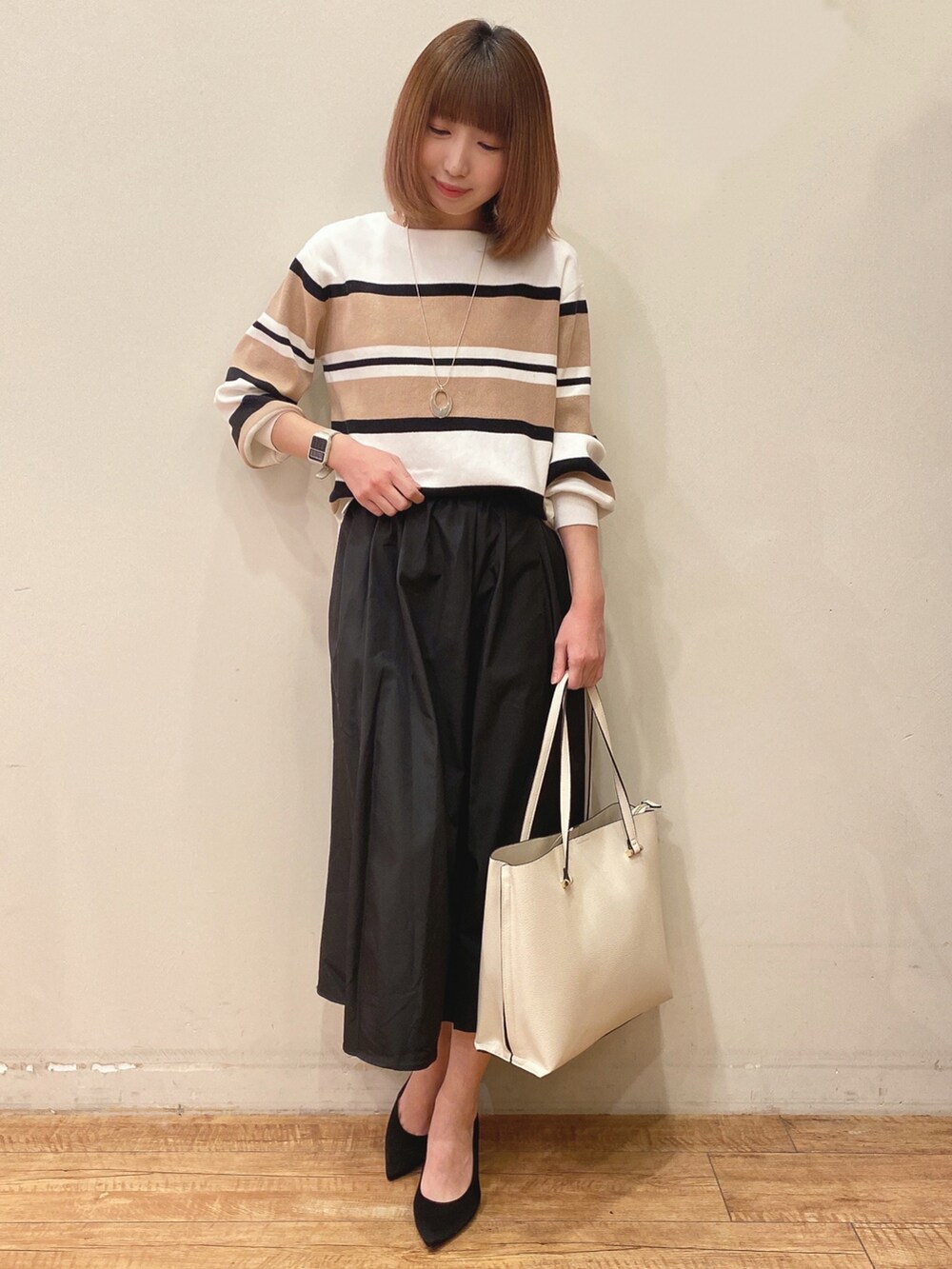 ベージュ系のニット/セーター、ブラック系のスカート、ホワイト系のトートバッグを着用したレディースの冬コーディネートの2枚目の写真