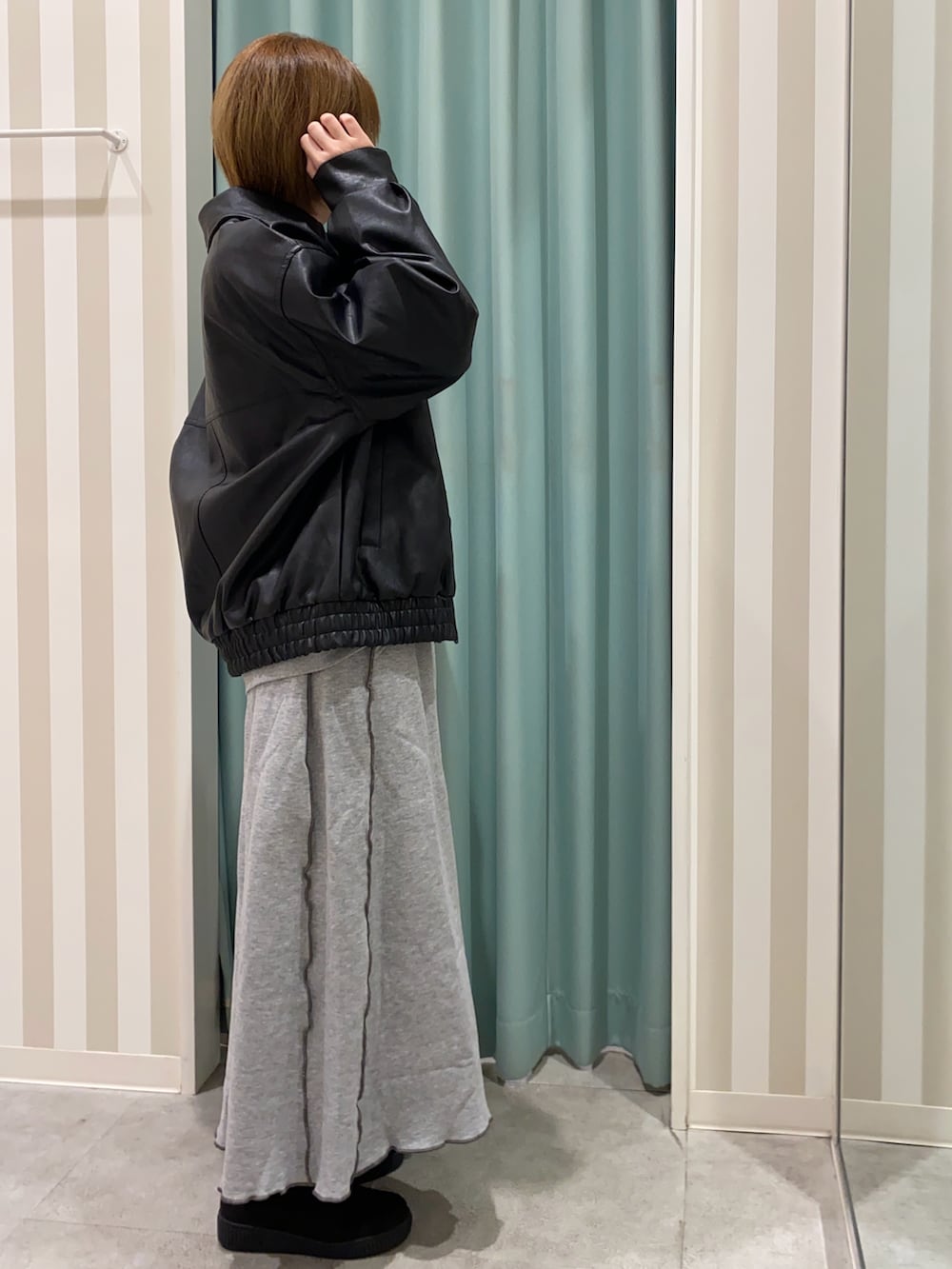 ブラック系のブルゾン、グレー系のスカート、ブラック系のブーツを着用したレディースの秋コーディネートの2枚目の写真