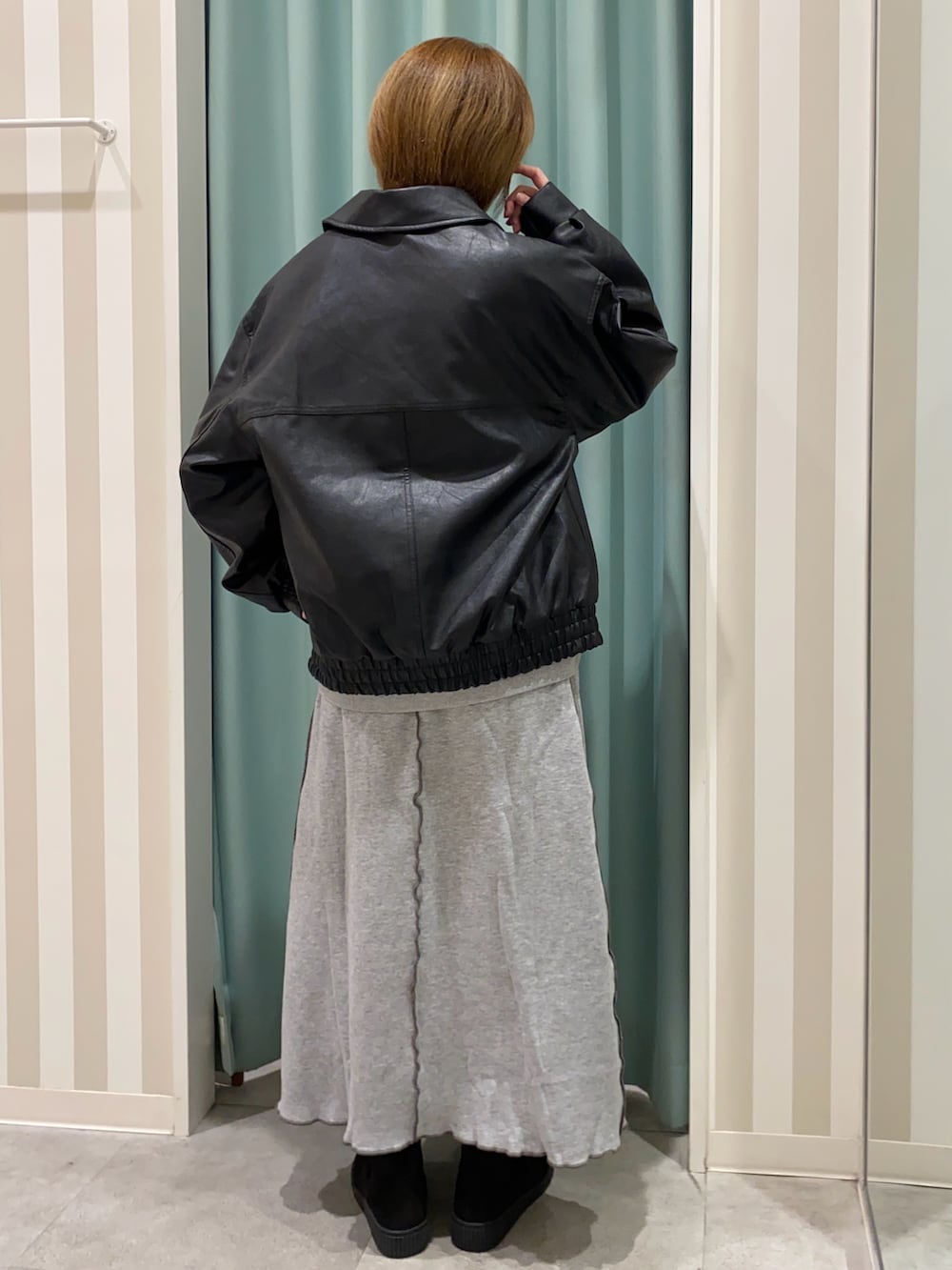 ブラック系のブルゾン、グレー系のスカート、ブラック系のブーツを着用したレディースの秋コーディネートの3枚目の写真