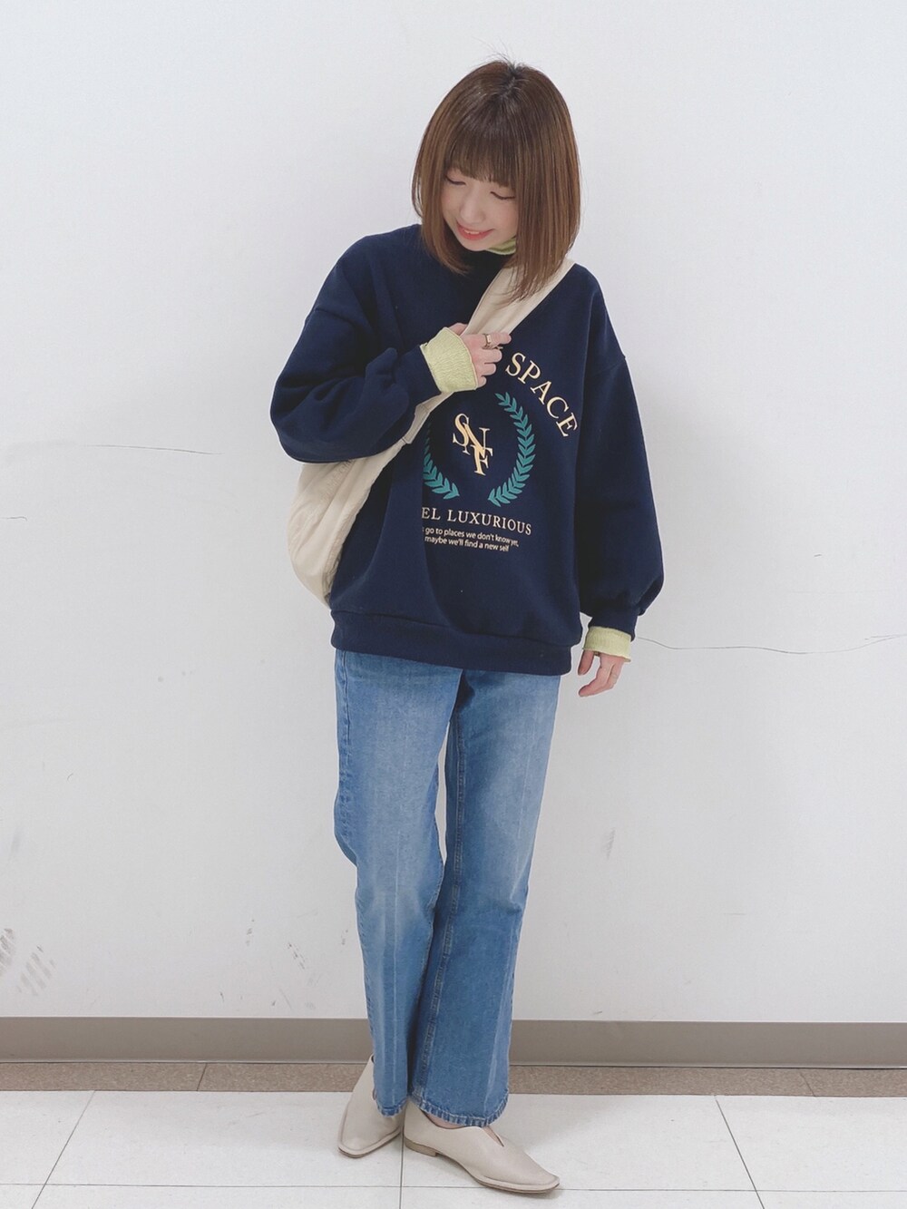 ブルー系のスウェット、ホワイト系のパンプス、ベージュ系のショルダーバッグを着用したレディースの冬コーディネートの4枚目の写真