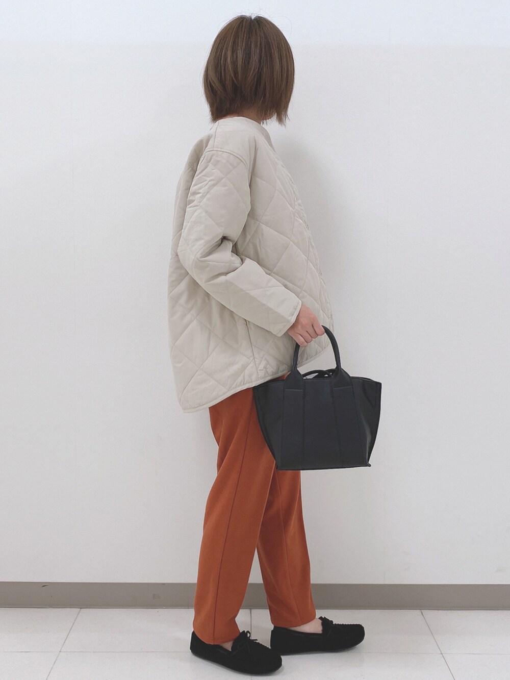 グレー系のブルゾン、ホワイト系のニット/セーター、オレンジ系のその他パンツを着用したレディースの秋コーディネートの2枚目の写真