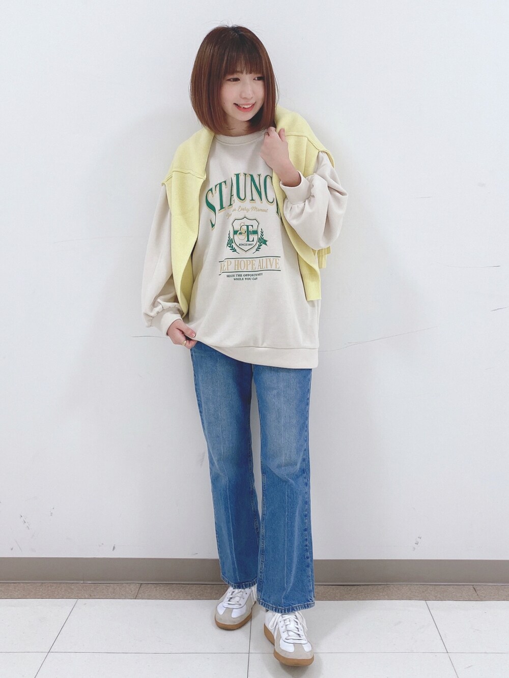 ベージュ系のスウェット、イエロー系のニット/セーター、ブルー系のデニムパンツを着用したレディースの冬コーディネートの4枚目の写真