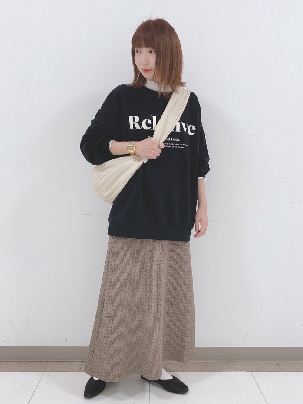ブラック系のスウェット、ベージュ系のスカート、ブラック系のパンプスを着用したレディースの春コーディネートの4枚目の写真