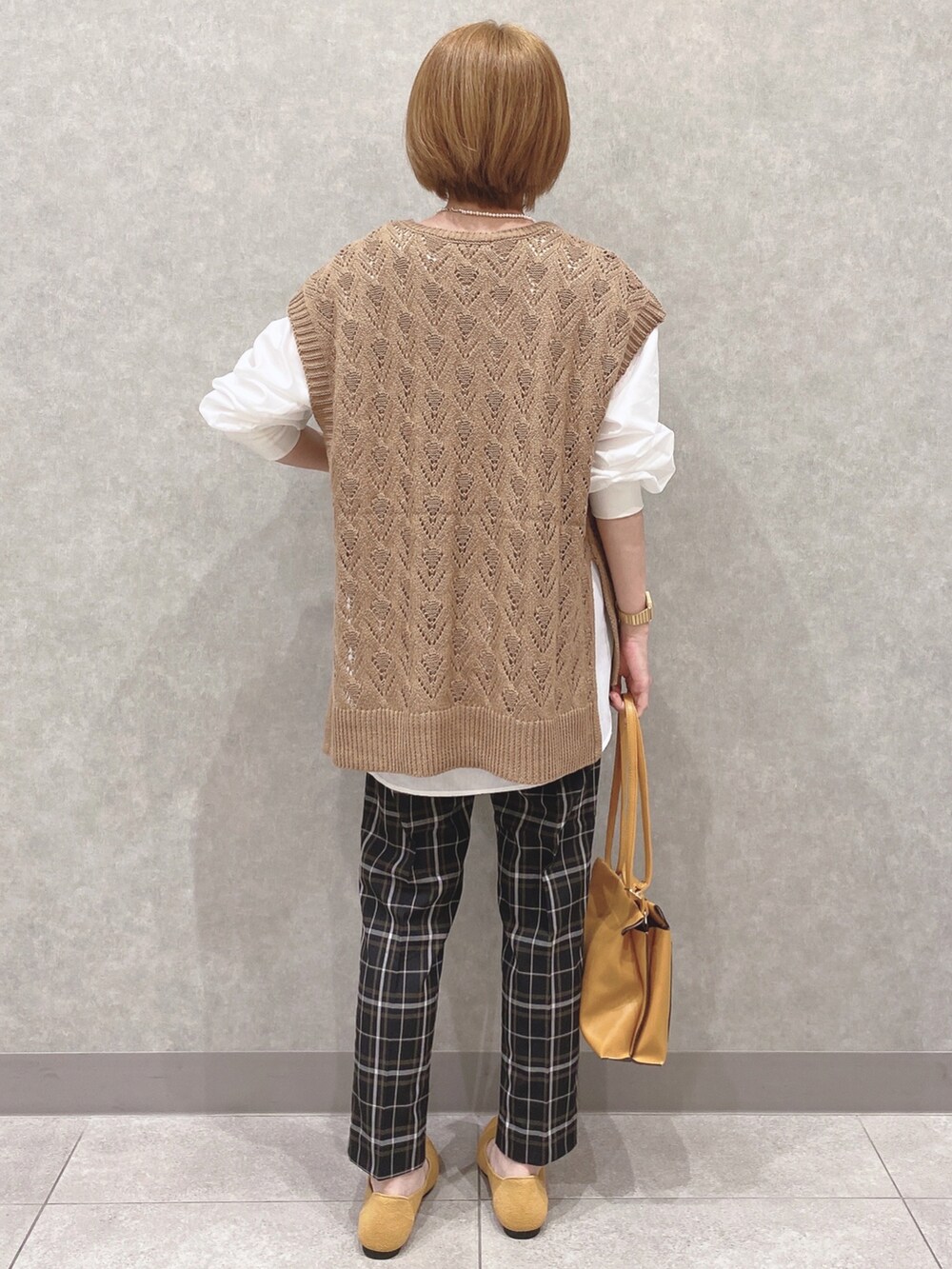 イエロー系のベスト、ホワイト系のシャツ/ブラウス、ブラック系のパンツを着用したレディースの夏コーディネートの3枚目の写真