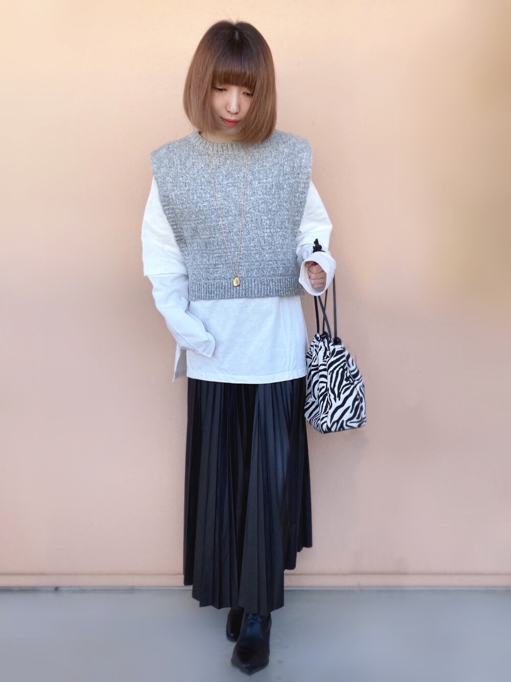 ブラック系のスカート、ブラック系のショルダーバッグ、ブラック系のブーツを着用したレディースの冬コーディネートの2枚目の写真