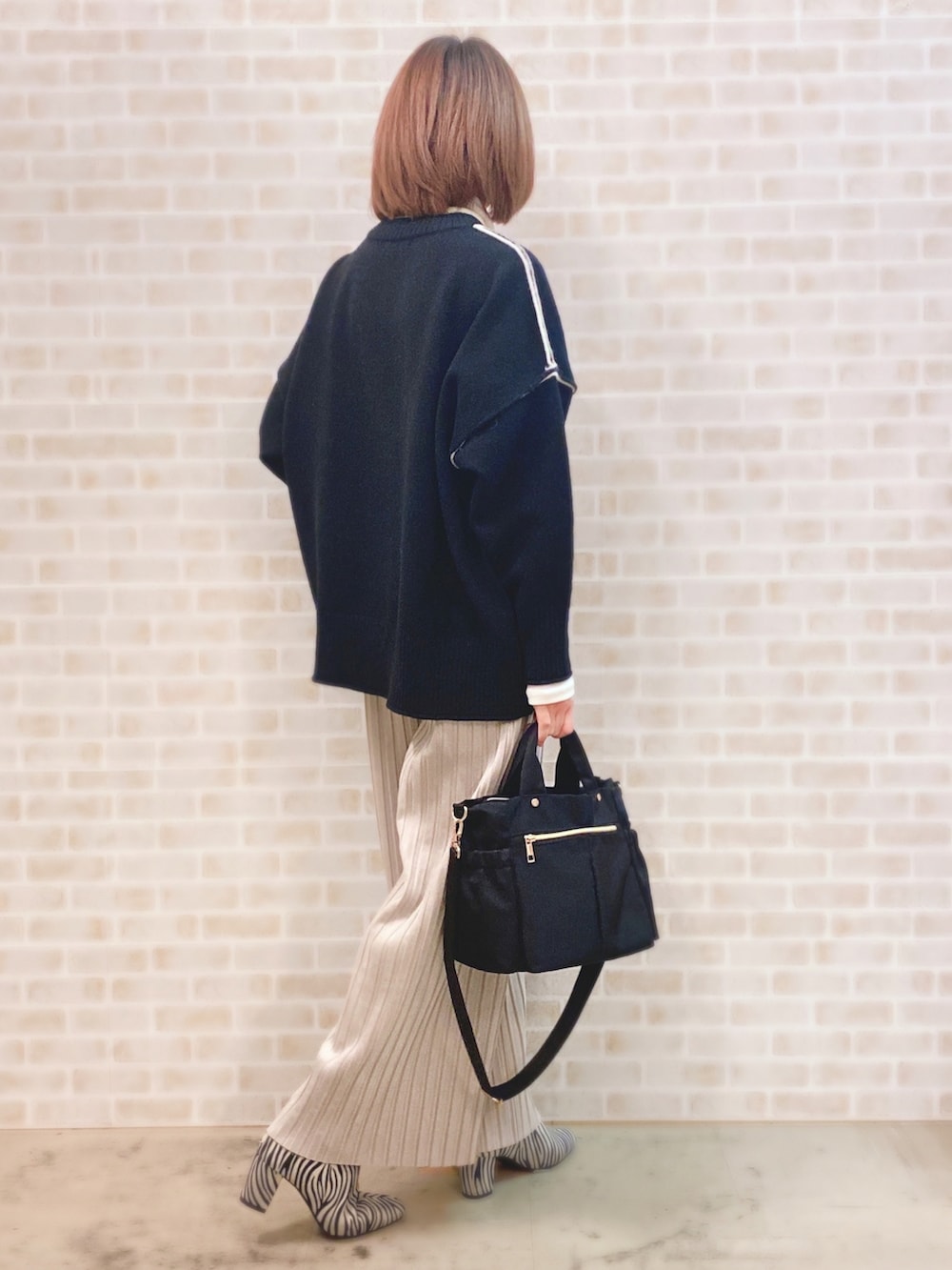 ブラック系のニット/セーター、ホワイト系のTシャツ/カットソー、グレー系のその他パンツを着用したレディースの冬コーディネートの2枚目の写真