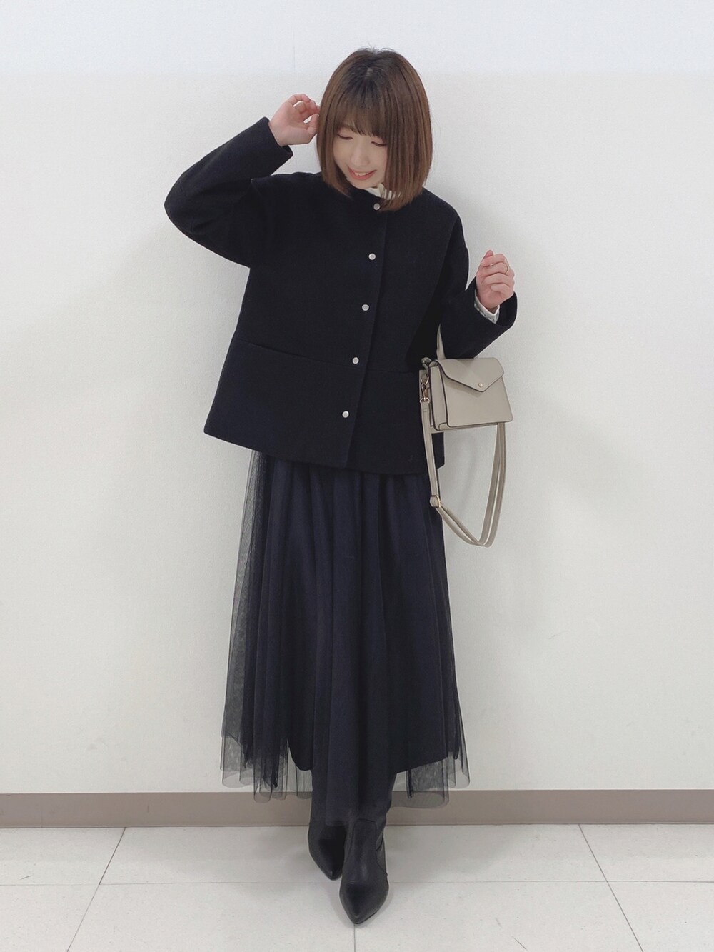 ブラック系のノーカラーコート、ホワイト系のシャツ/ブラウス、ブラック系のスカートを着用したレディースの冬コーディネートの4枚目の写真