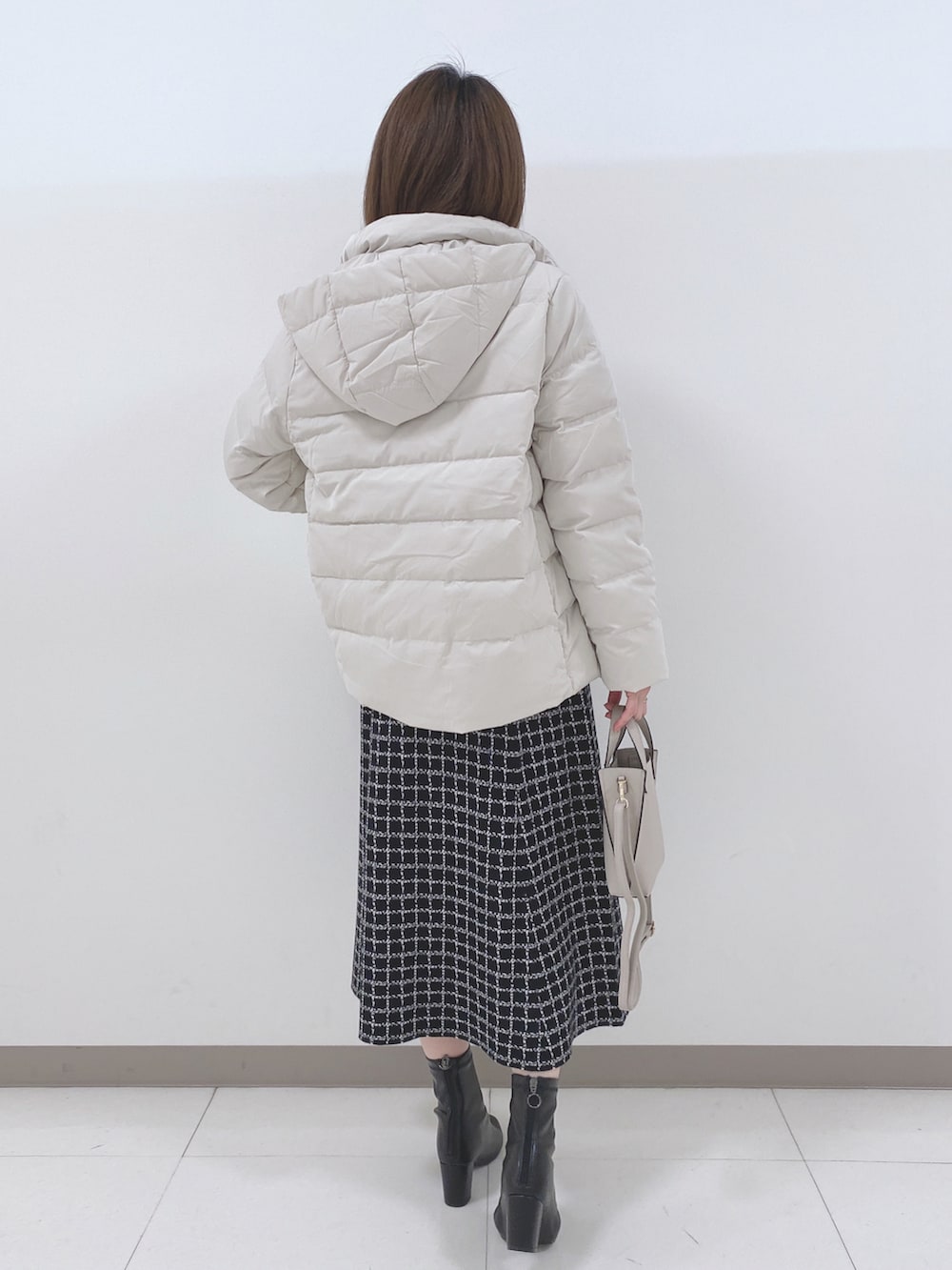 ベージュ系のダウンジャケット/コート、ブラック系のニット/セーター、ブラック系のスカートを着用したレディースの冬コーディネートの3枚目の写真