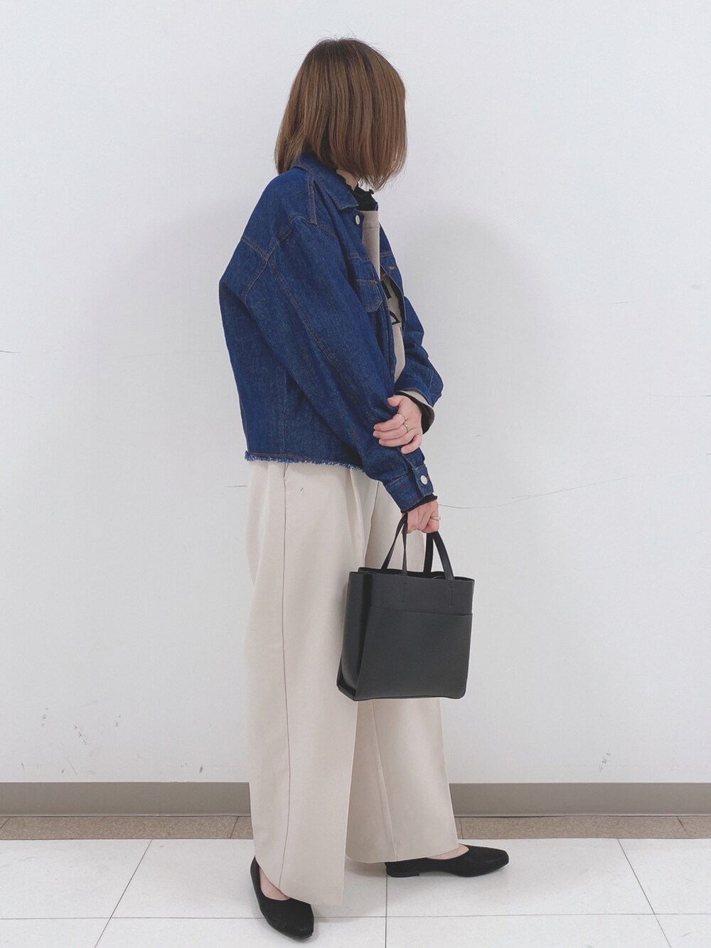 ブルー系のデニムジャケット、ベージュ系のニット/セーター、ベージュ系のその他パンツを着用したレディースの春コーディネートの2枚目の写真