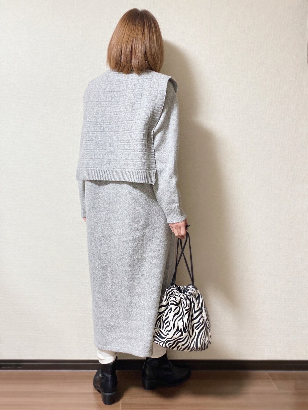 グレー系のワンピース、ブラック系のショルダーバッグ、ブラック系のブーツを着用したレディースの冬コーディネートの2枚目の写真