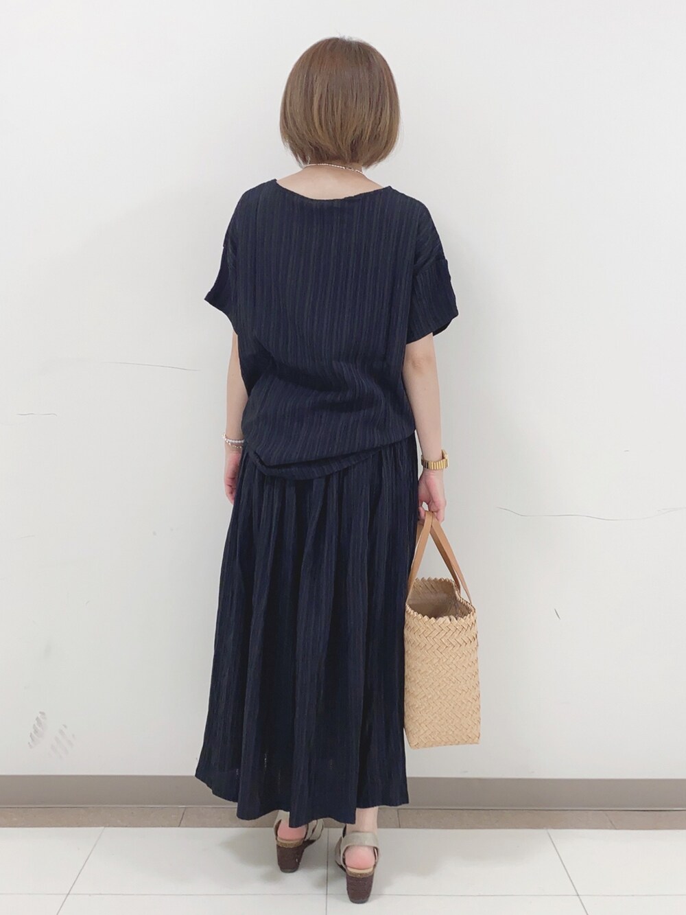 ブラック系のTシャツ/カットソー、ブラック系のスカート、ゴールド系のサンダルを着用したレディースの夏コーディネートの3枚目の写真