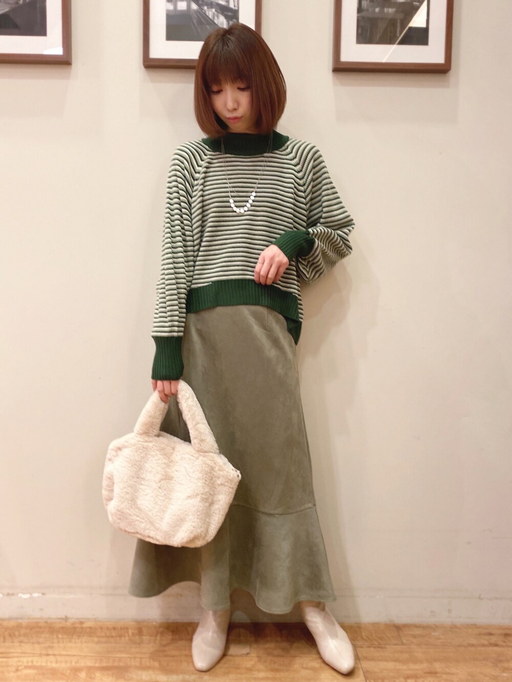 グリーン系のニット/セーター、グリーン系のスカート、ホワイト系のブーツを着用したレディースの冬コーディネートの3枚目の写真
