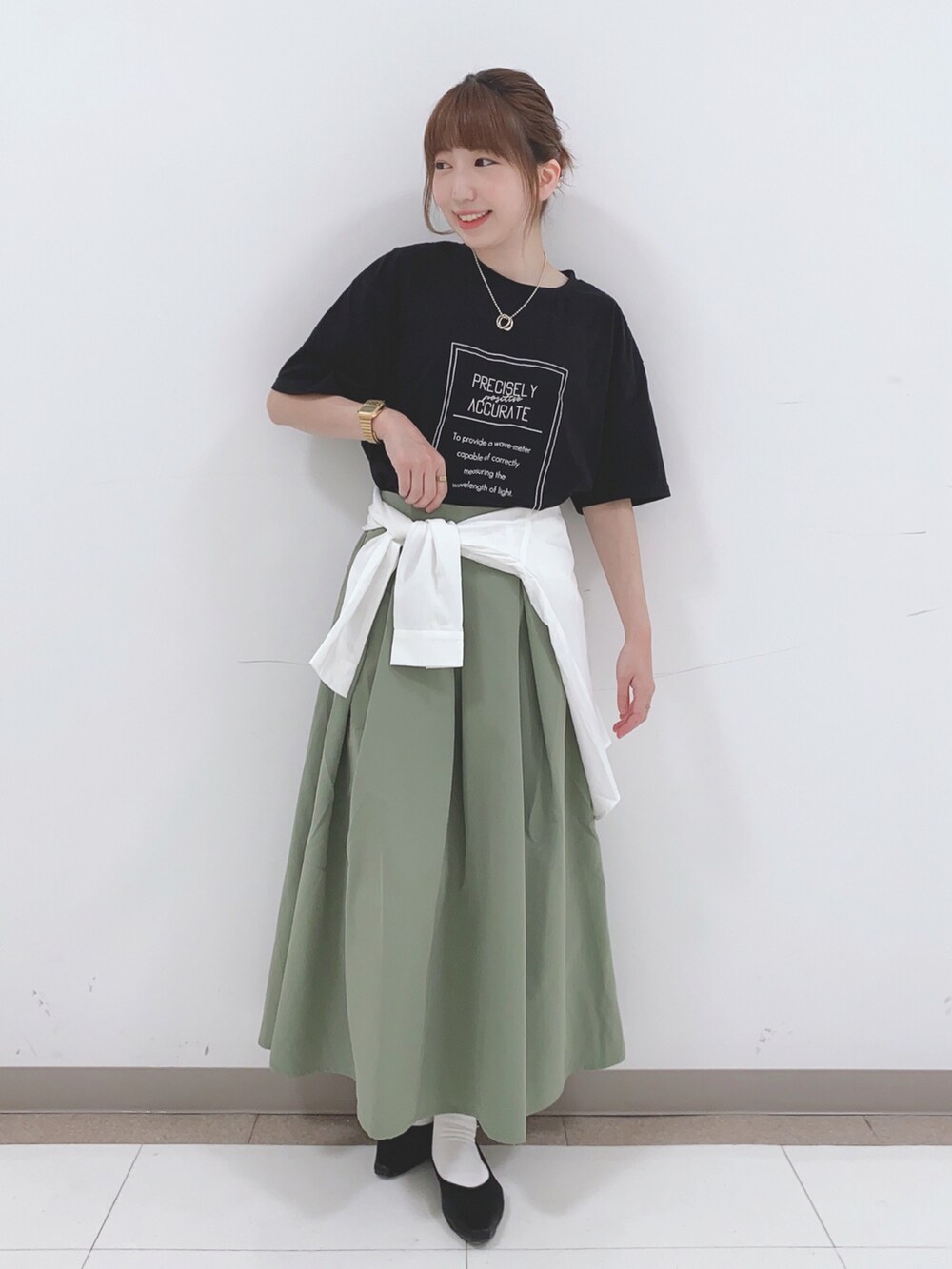 ブラック系のTシャツ/カットソー、グリーン系のスカート、ホワイト系のシャツ/ブラウスを着用したレディースの春コーディネートの4枚目の写真
