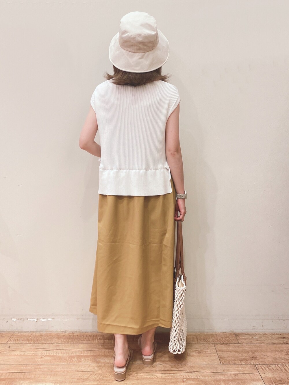 イエロー系のワンピース、ホワイト系のトートバッグ、ベージュ系のサンダルを着用したレディースの春コーディネートの3枚目の写真