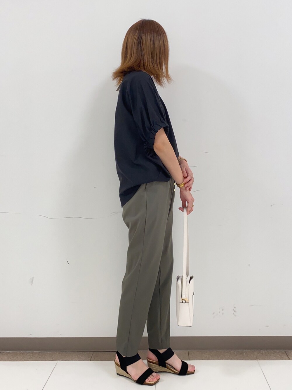 ブラック系のTシャツ/カットソー、グリーン系のその他パンツ、ホワイト系のショルダーバッグを着用したレディースの春コーディネートの2枚目の写真