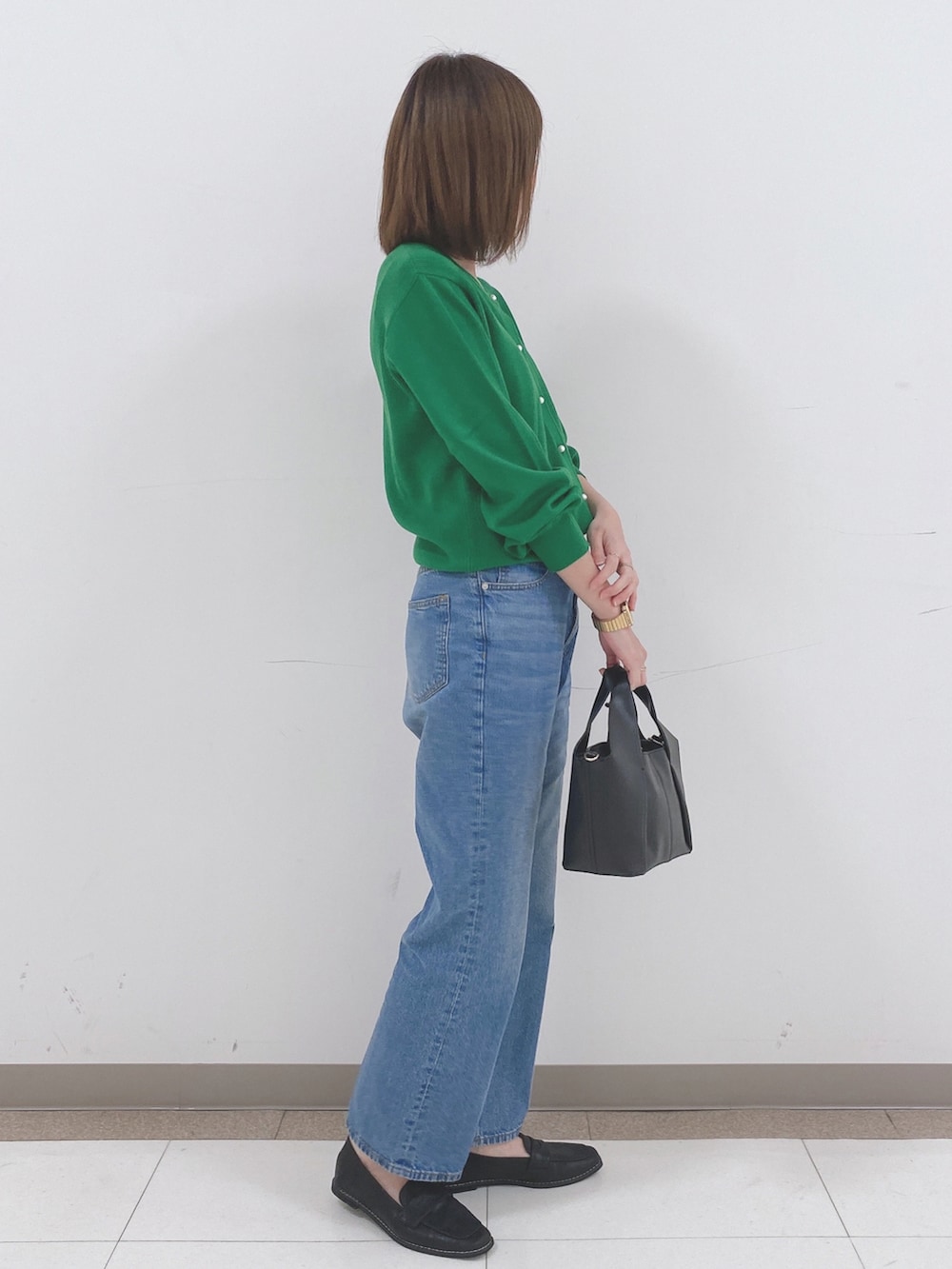 グリーン系のカーディガン/ボレロ、ブルー系のデニムパンツ、ブラック系のスニーカーを着用したレディースの冬コーディネートの2枚目の写真