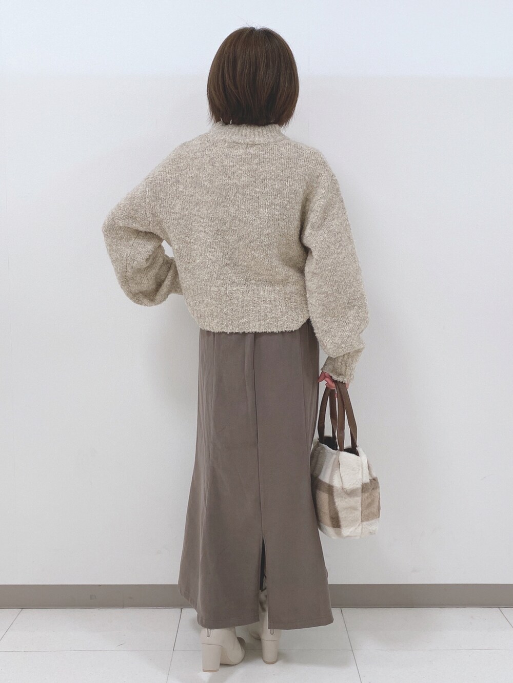 ベージュ系のニット/セーター、ブラウン系のスカート、ホワイト系のブーツを着用したレディースの秋コーディネートの3枚目の写真