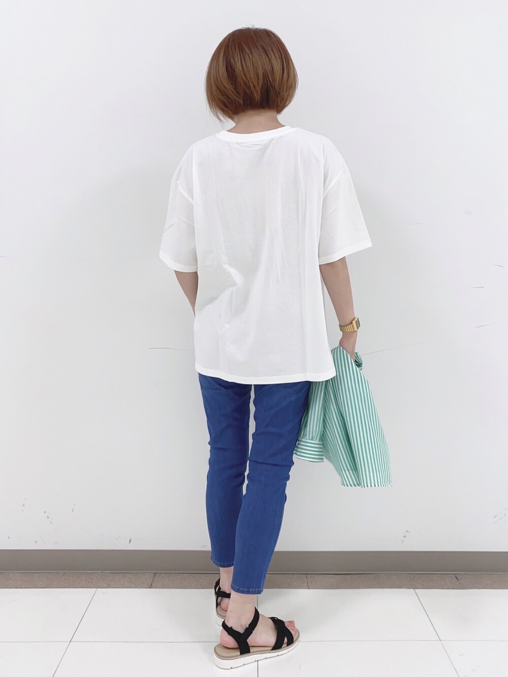 グリーン系のシャツ/ブラウス、ホワイト系のTシャツ/カットソー、ブルー系のデニムパンツを着用したレディースの春コーディネートの3枚目の写真