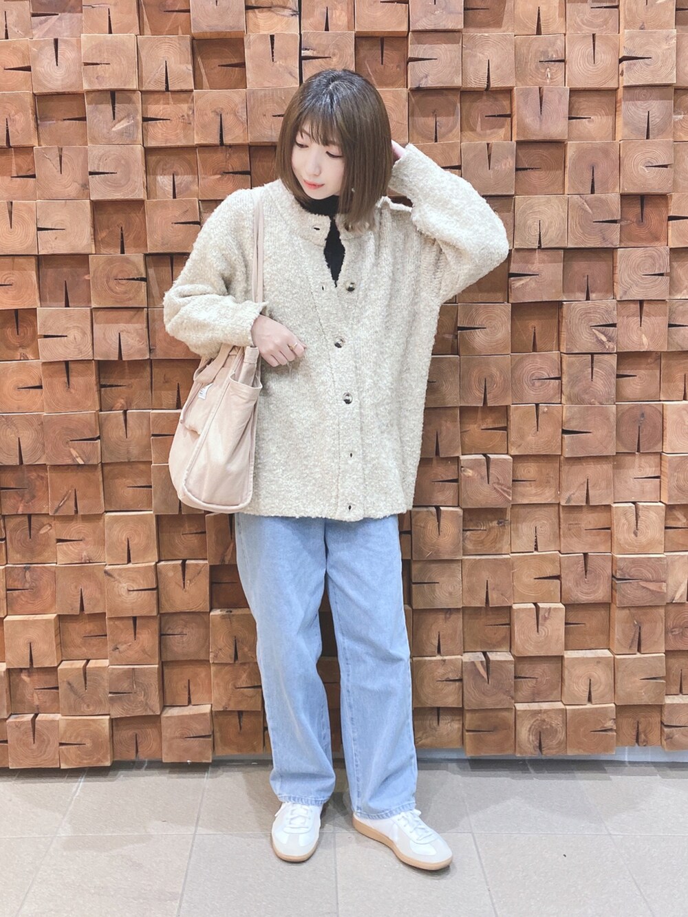 ベージュ系のカーディガン/ボレロ、ブラック系のニット/セーター、ブルー系のデニムパンツを着用したレディースの冬コーディネートの4枚目の写真