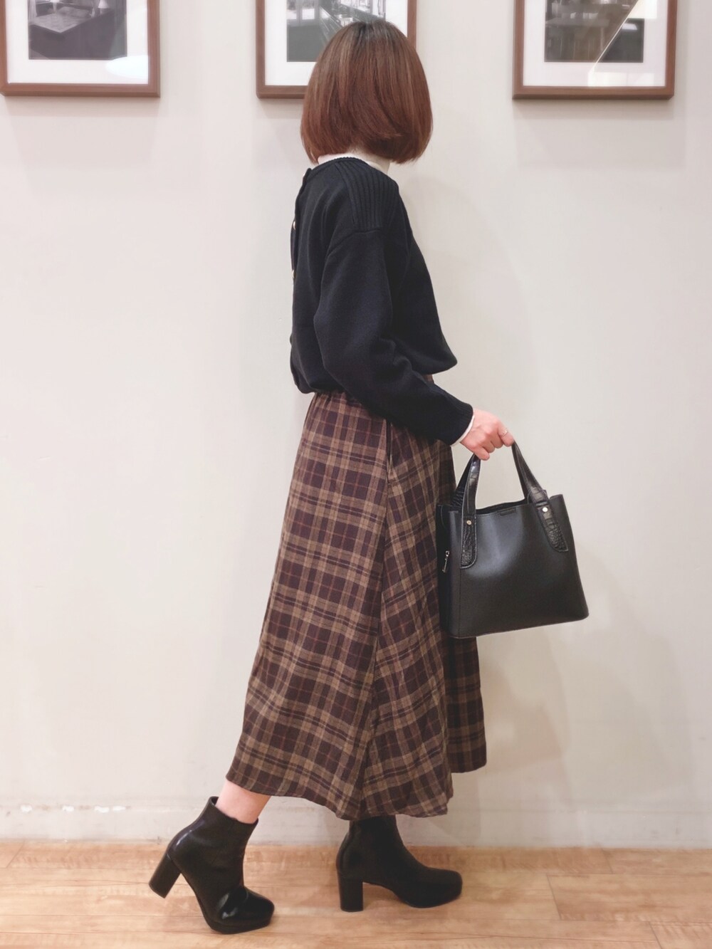 ブラック系のニット/セーター、ブラウン系のスカート、ブラック系のトートバッグを着用したレディースの秋コーディネートの2枚目の写真