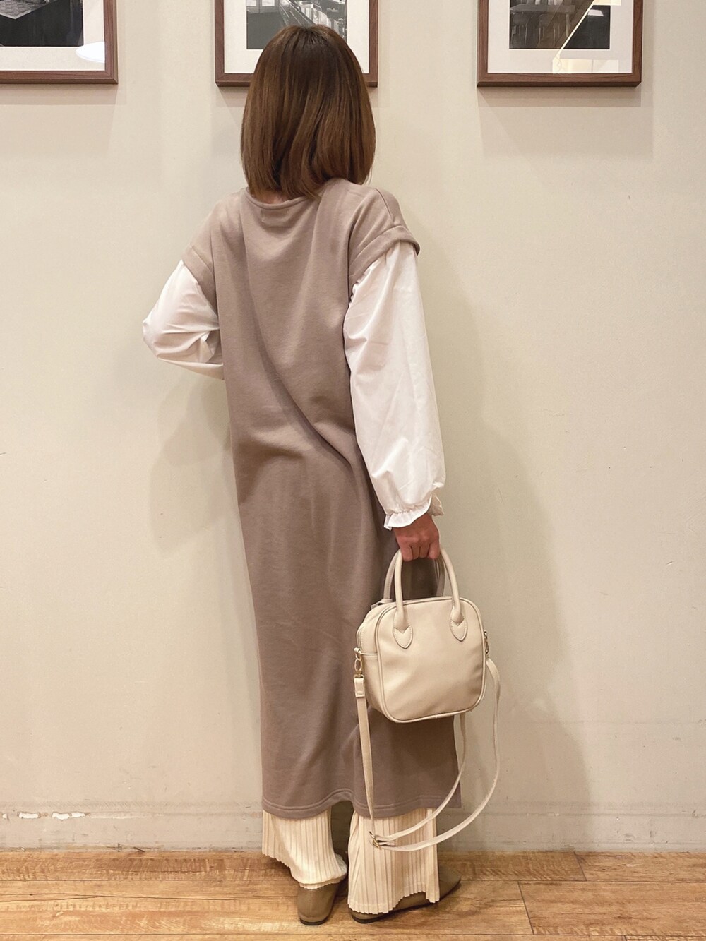 ベージュ系のワンピース、ベージュ系のパンプス、ホワイト系のショルダーバッグを着用したレディースの冬コーディネートの2枚目の写真