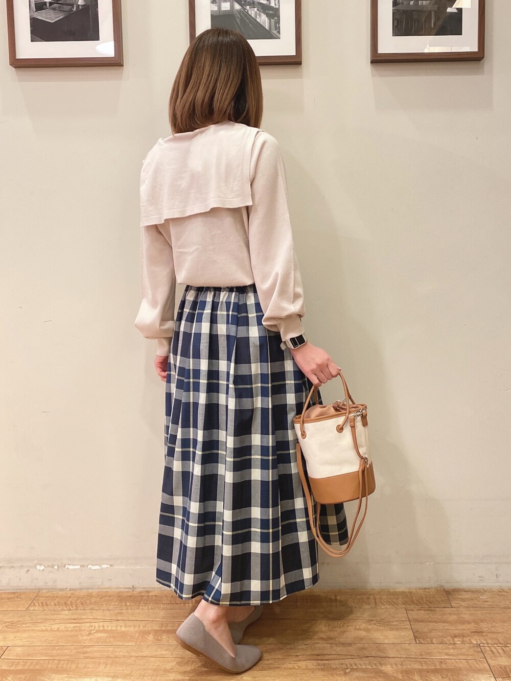 ベージュ系のニット/セーター、ブルー系のスカート、ブラウン系のハンドバッグを着用したレディースの冬コーディネートの2枚目の写真