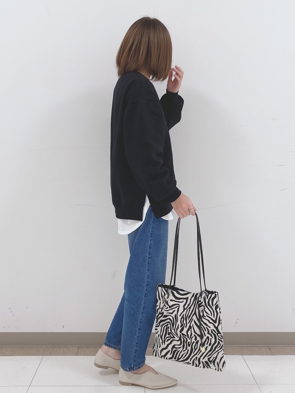 ブラック系のスウェット、ホワイト系のTシャツ/カットソー、ブルー系のデニムパンツを着用したレディースの冬コーディネートの2枚目の写真