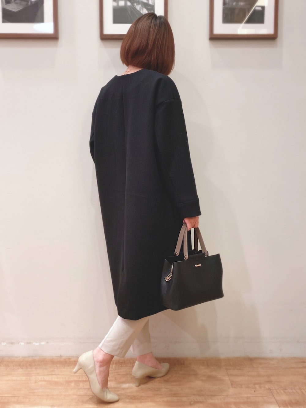 ブラック系のトートバッグ、ブラック系のノーカラーコート、ベージュ系のチュニックを着用したレディースの秋コーディネートの2枚目の写真