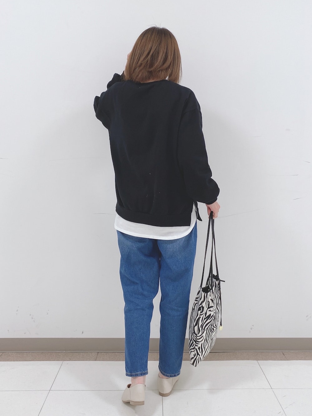 ブラック系のスウェット、ホワイト系のTシャツ/カットソー、ブルー系のデニムパンツを着用したレディースの冬コーディネートの3枚目の写真