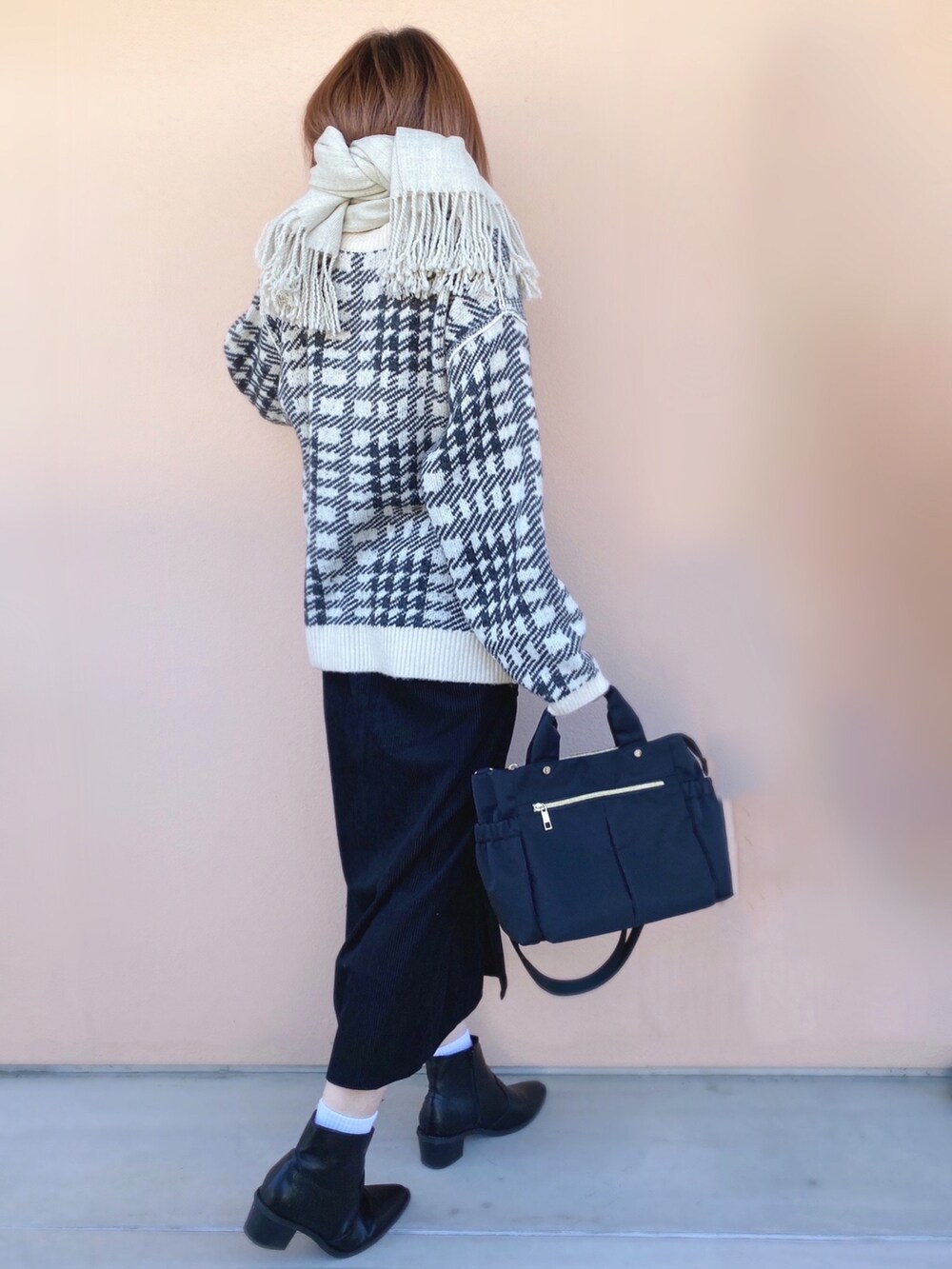 ホワイト系のニット/セーター、ブラック系のトートバッグ、ブラック系のスカートを着用したレディースの冬コーディネートの2枚目の写真