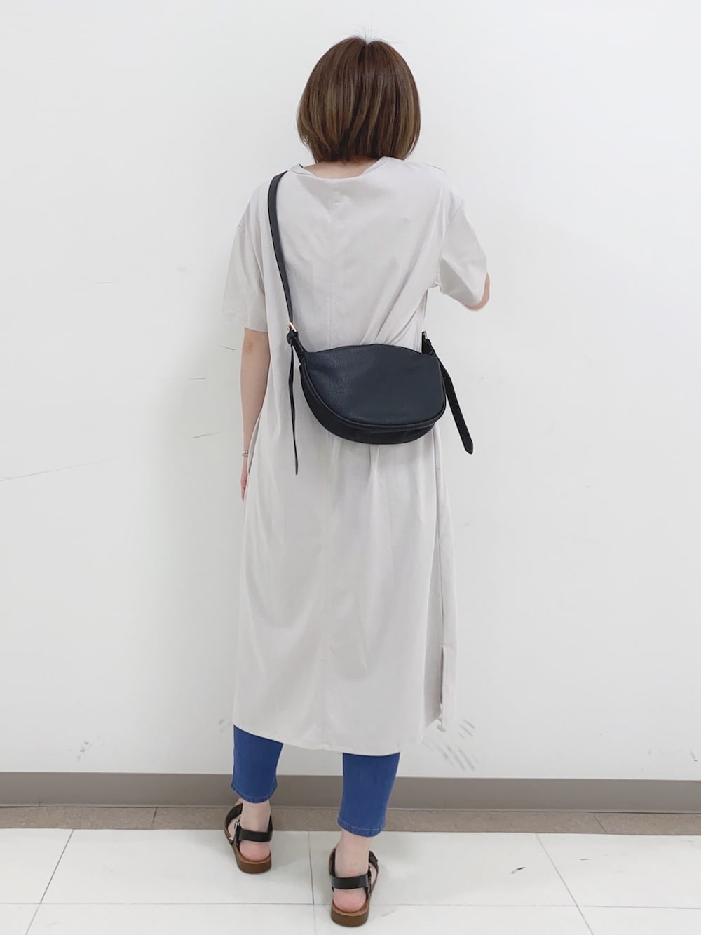 グレー系のワンピース、ブルー系のデニムパンツ、ブラック系のサンダルを着用したレディースの夏コーディネートの3枚目の写真