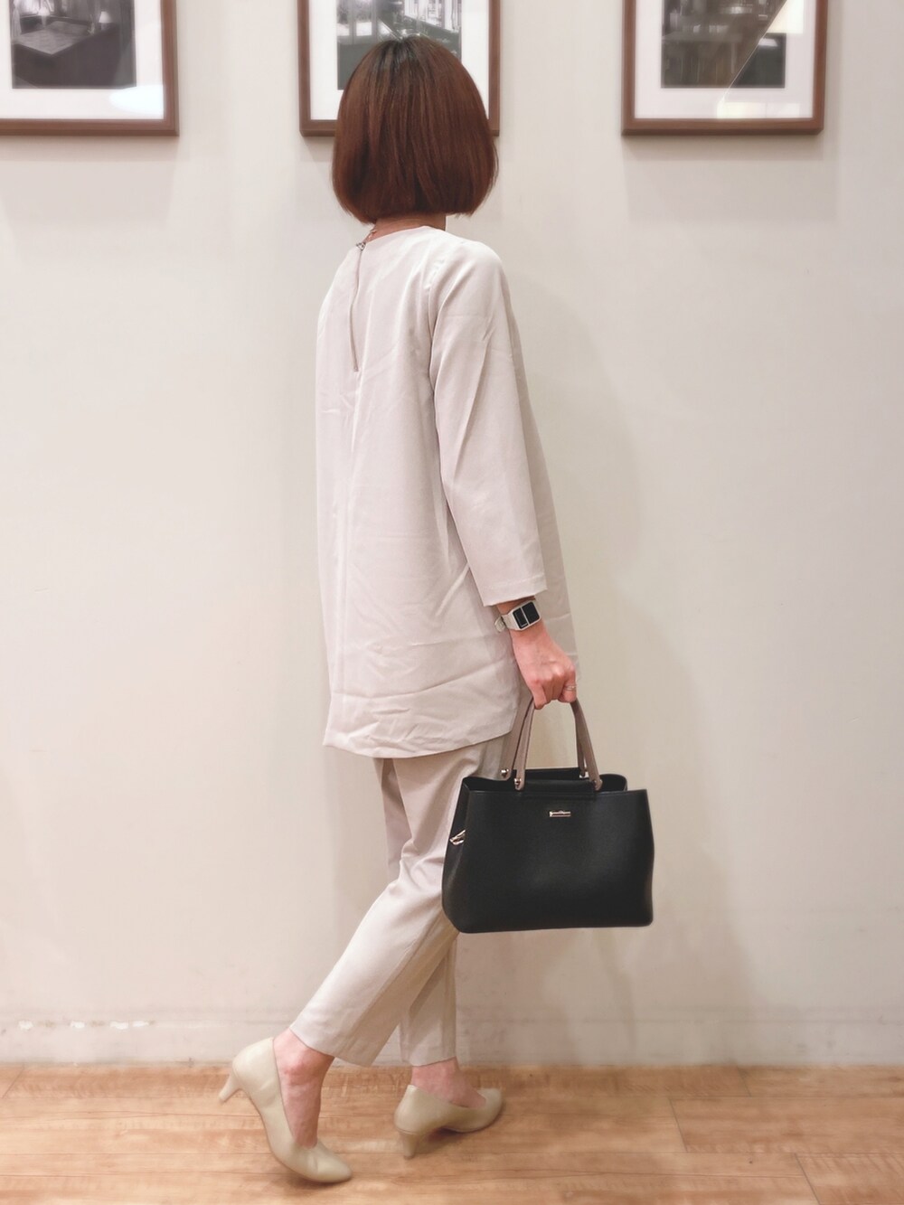 ブラック系のトートバッグ、ブラック系のノーカラーコート、ベージュ系のチュニックを着用したレディースの秋コーディネートの4枚目の写真