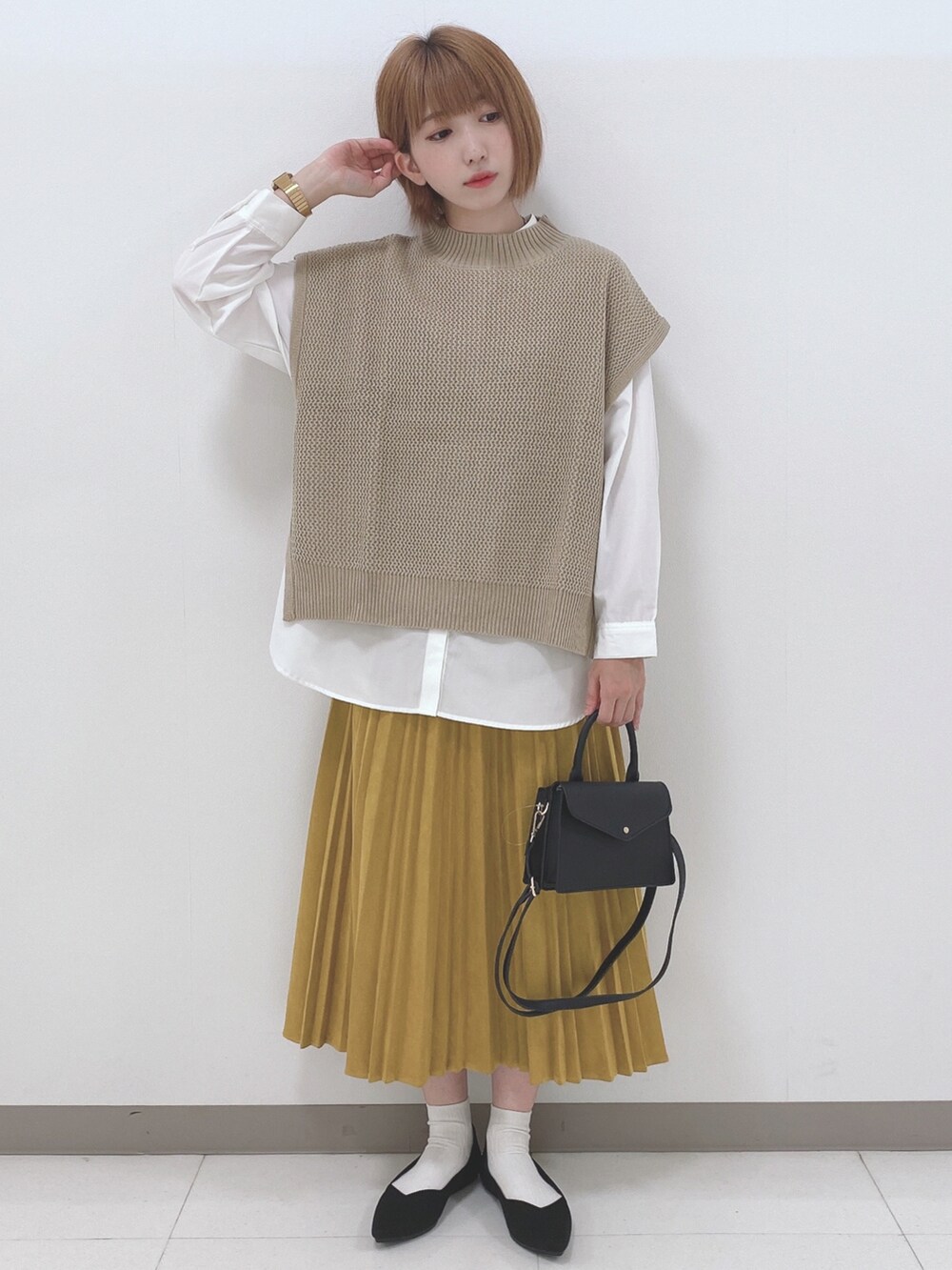 ベージュ系のベスト、ホワイト系のシャツ/ブラウス、イエロー系のスカートを着用したレディースの秋コーディネートの4枚目の写真