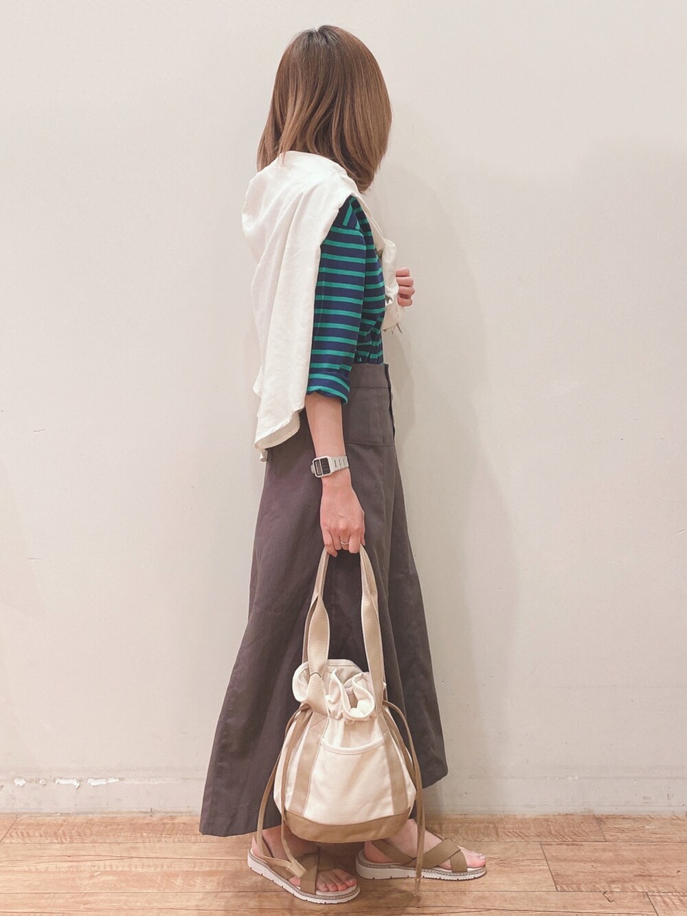 ブルー系のTシャツ/カットソー、ホワイト系のシャツ/ブラウス、グレー系のスカートを着用したレディースの春コーディネートの2枚目の写真